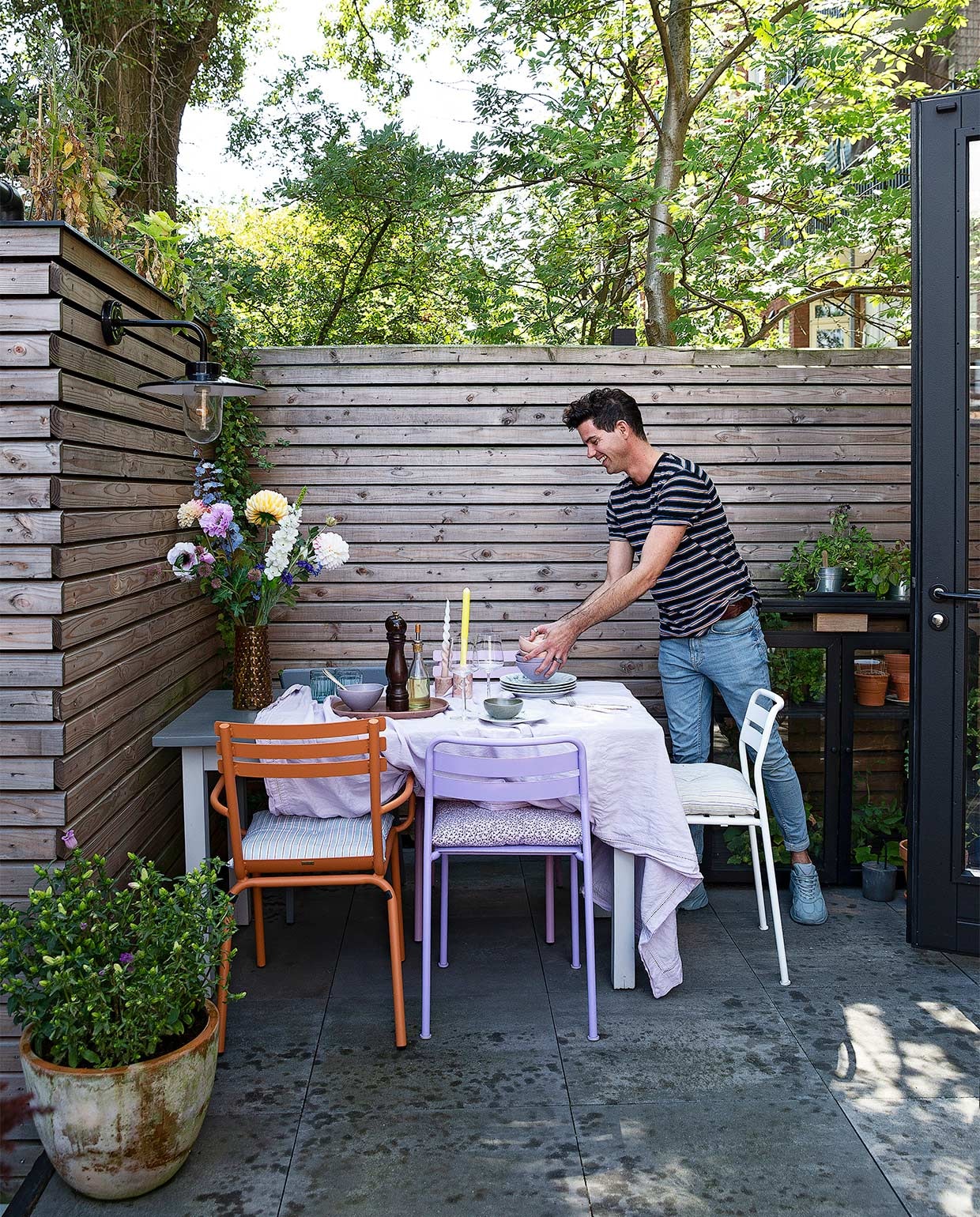Oranje stoel, roze stoel Sissy-Boy, lila stoel, witte stoel Ikea, grijze stoel Dille &amp; Kamille. Kussens, vaas, dienblad Søstrene Grene, pepermolen Peugeot, kandelaars Karwei, servies familiestuk, schaaltjes Sissy-Boy, groene glazen, wijnglazen Iittala. Zilveren bestek Marktplaats, lamp aan de schutting KS Verlichting. NEE  | vtwonen binnenkijken special 2021 | Fotografie Jansje Klazinga | Styling Roy Seen