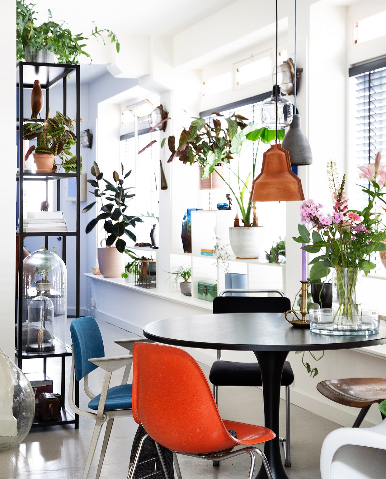 Hangplant Intratuin, hanglampen van links naar rechts Seen Design, Normann Copenhagen, Puik Design. Tafel Woood, houten stoel, oranje stoel, blauwe stoel De Machinekamer, witte stoel Verner Panton. Vaas Bloomon, fruitschaal Kwantum, kandelaar, lage tafel familiestuk, mokken HKliving. Pelletkachel Nordic Fire, witte vaas Hema, glazen kandelaar met rode kaars Sissy-Boy, ornament kwal Bijenkorf, zwarte theepot Bredemeijer, witte vaas Bloomon. Grote groene bloempot 123planten, lage tafel Vestbjerg Jens, witte bloempot D&amp;M deco. NEE  | vtwonen binnenkijken special 2021 | Fotografie Jansje Klazinga | Styling Roy Seen