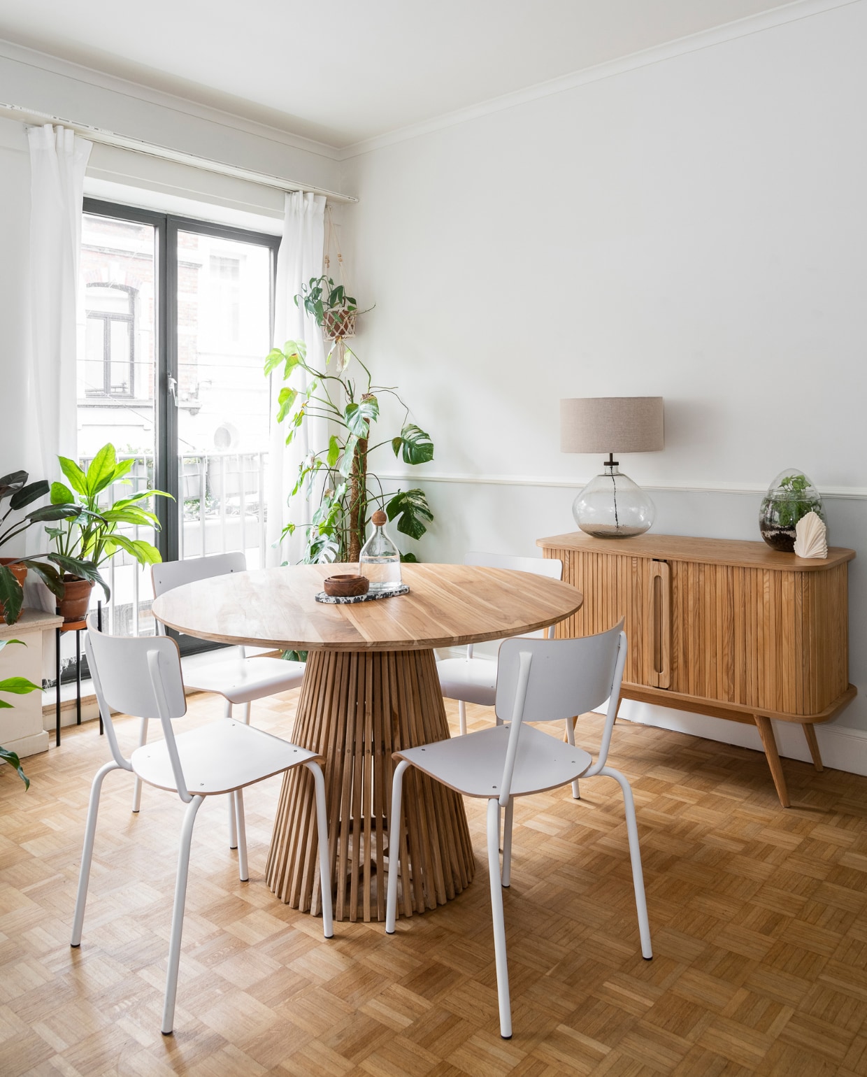 Stoelen Perfecta, ronde tafel en dressoir Fonq, waterkaraf H&amp;M home, tafellamp Sissy-Boy, kaars Soy Hive Candles. Vloerkleed Karwei, bank Lazy van vtwonen, kussen zelfgemaakt. Tafel Made, kan van rommelmarkt. De bijzettafel Marktplaats. Terrarium met planten zelf gemaakt, gordijnen Ikea, plantenhanger uit Bali. vtwonen 09-2022 | Fotografie Jonah Samyn | Tekst Katrien Depoorter