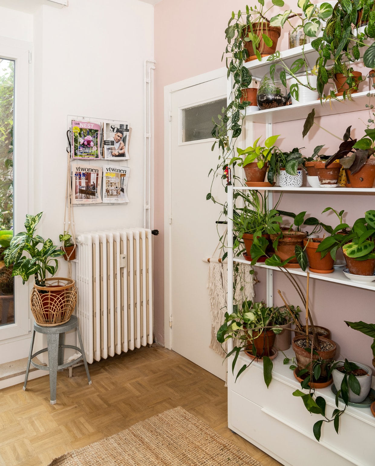 Muren geschilderd in Lovely White WE Z042 en roze (nummer onbekend) van Boss Paints via Colora. Groot wit rek, tapijt Ikea, tijdschriftenrek Hema. Metalen kruk Sissy-Boy, bloempot H&amp;M Home. vtwonen 09-2022 | Fotografie Jonah Samyn