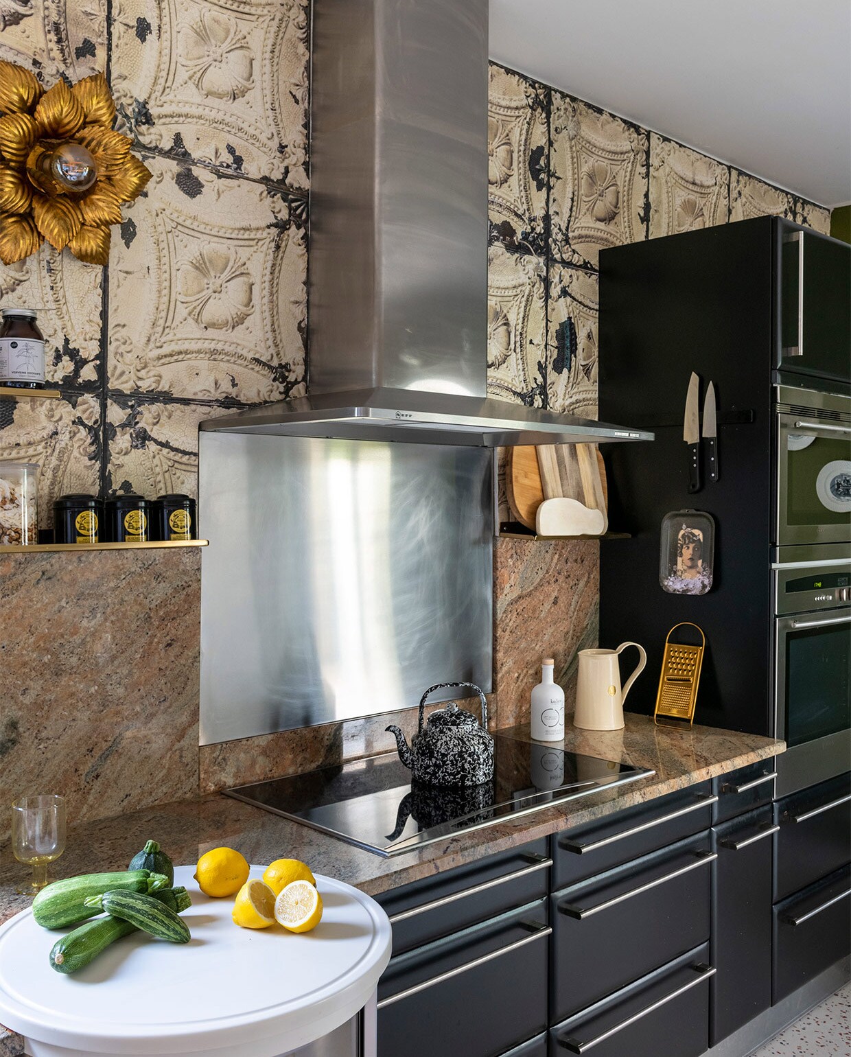 Keukenkastjes zwart geschilderd, vloer terrazzo-print linoleum van Gerflor, behang Merci voor Arte, muurverf kleur Bancha van Farrow&amp;Ball, tafel La Redoute, barkrukken vintage, hanglamp Ay Illuminate, planken House Doctor, muurlampen tweedehands, schilderij konijn Ibride, Chinese borden aan de muur antiek, gouden glazen Miss Étoile, theepot Merci Paris, waterkan Anthropologie. Overig onbekend of vintage. vtwonen binnenkijken special 2021 | productie A&amp;J | fotografie Julien Fernandez