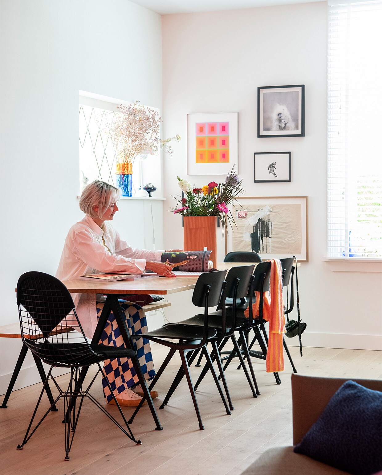 Tafel, bank en stoelen Ahrend voor Hay. Draadstoel Charles &amp; Ray Eames van DKR/Vitra. Grote vaas Muuto. Vaas blauw en oranje glasfabriek Beldi in Marrakesh. Vintage zeefdruk van Richard Anuszkiewicz. Werk Mika van Chris Berens. Klein zwart-wit werk van Daniel Berio. Pentekening in zwarte lijst van Kim David Bots. Landschap in houten lijst van Aldo van den Broek. NEE | vtwonen binnenkijken special 2021 | productie Insidehomepage | styling Kim Timmerman | fotografie Louis Lemaire
