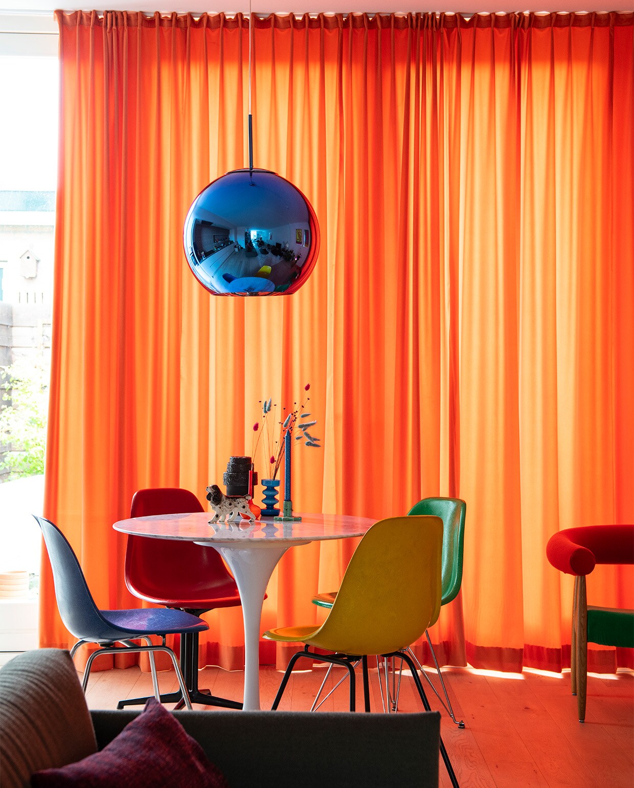 Tulip tafel Eero Saarinen. Stoelen vintage Charles &amp; Ray Eames van Herman Miller/Vitra. Hanglamp Tom Dixon. Zwarte vaas Rudolph Schelling Webermann (RSW). Blauwe vaas van vintagewinkel in Eindhoven. Oranje vaas uit een tweedehandswinkel in Berlijn. Groene kandelaar en beeldje vintage. Fruitschaal Ann Demeulemeester, Serax. Wandtegels tegelsinhuis.nl. Rest onbekend. NEE | vtwonen binnenkijken special 2021 | productie Insidehomepage | styling Kim Timmerman | fotografie Louis Lemaire