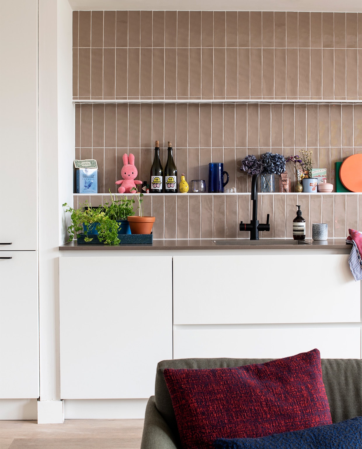 Wandtegels tegelsinhuis.nl. Zwarte kraan Hotto. Bank Muuto. Kussens Kvadrat Raf Simons. Op aanrecht: vintage spiegel kringloop, snijplanken en plumeau Hay, dienblad Zara Home. NEE | vtwonen binnenkijken special 2021 | productie Insidehomepage | styling Kim Timmerman | fotografie Louis Lemaire