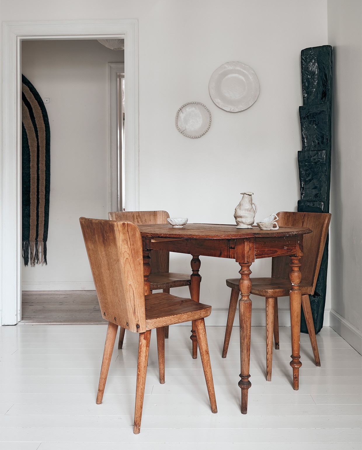 Borden aan de muur en keramiek op tafel gemaakt door Ellen. Houten object winkeldecoratie By Malene Birger, Zweedse tafel vintage, vintage stoelen Gøran Malmvall. Aan de muur in de gang kleed Cappelen Dimyr no.06, NEE | vtwonen binnenkijken special 2021 | productie Living Inside | fotografie Christoffer Regild