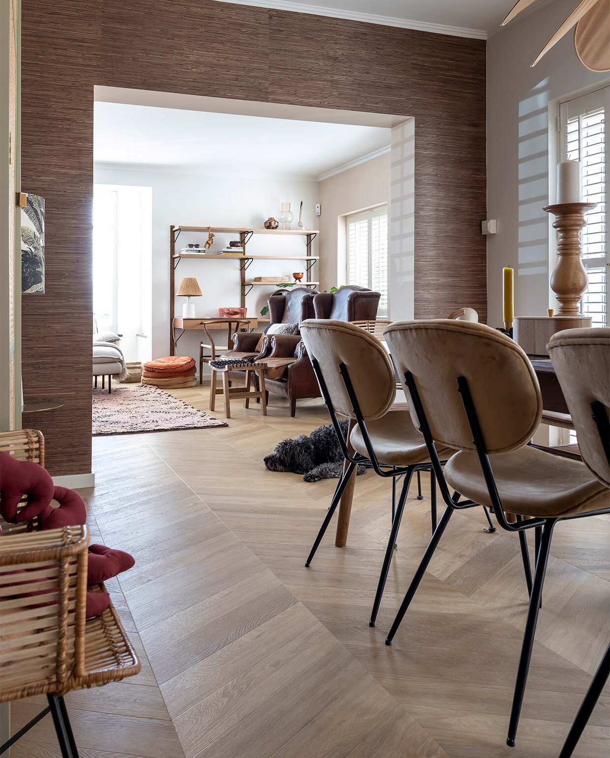 Muurkleur Flexa Gentle Umber. Behang Eijffinger Natural grasweefsel. Vloer Hongaarse punt pvc Therdex 6541. Houten stoelen Wishbone Chair, uitschuifbare tafel Sohome, gele kaars Sissy-Boy, kaarsenstandaard Loft Arnhem, rotan stoelen en drie stoelen rechts, rond kussen, kleed en plantentafel HKliving. Kast en spiegel Ikea Stockholm-lijn, vaasjes Zara home, lamp Archive Store. Shutters Veneta. vtwonen binnenkijken special 12-2021 | fotografie Henny van Belkom