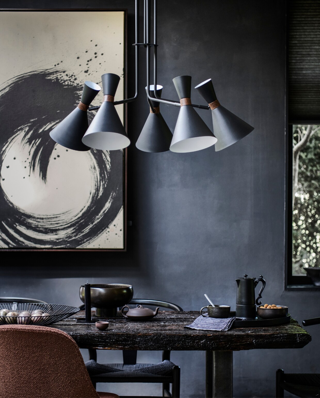Matzwarte metalen hanglamp Hoodies, 86,5×89 cm (Øxh) (ook verkrijgbaar in mat zandgrijs). M.m.v. tessaderijk.com (schilderij), loods5.nl (zwarte eetkamerstoelen), designtales.nl (bruin gestoffeerde eetkamerstoel, schaal en kom van Menu), vtwonen.nl (opengewerkte schaal van Serax), simonlevelt.nl (bruine keramieken theepot met kopje), letoile.store (theedoek), paviljoennoord.com (mok, koffiepot). Overig privébezit. vtwonen 10-2022 | productie Tanja Saarberg | styling Danielle Verheul | fotografie Sjoerd Eickmans