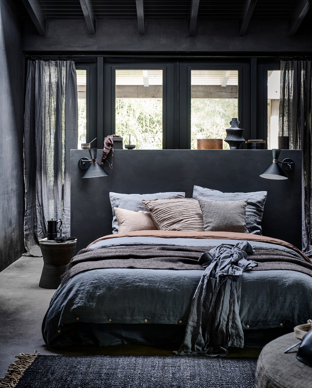 Matzwarte metalen wandlamp Hoodies, 25x25x50,5 cm (lxbxh) € 89,95 (ook verkrijgbaar in zandgrijs). M.m.v. bymolle.com (linnen laken in kleur Slate, linnen dekbedovertrek in kleur Slate en Cacao, linnen kussensloop in kleur Slate, linnen gordijnen in kleur Slate), letoile.store (vloerkleed, zwart houten bord, keramieken wierookhouder, beige linnen kussen), loods5.nl (keramieken bijzettafel, fauteuil), paviljoennoord.com (koffiepot, zwart-wit geruit kussen, leren tas), hm.com (plaid, bruin kussen, zwarte vaas, linnen ochtendjas), vtwonen.nl (houten mok van Serax). Overig privébezit. vtwonen 10-2022 | productie Tanja Saarberg | styling Danielle Verheul | fotografie Sjoerd Eickmans