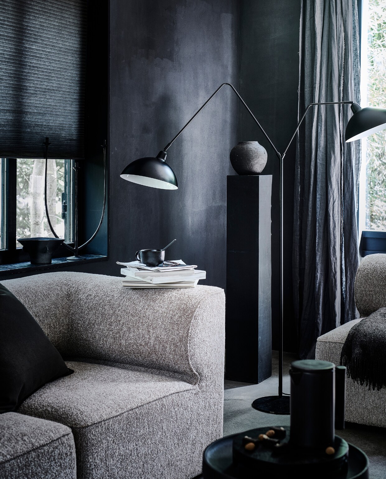 Matzwarte metalen vloerlamp Orion, 180×140 cm (hxb), kap en voetplaat 31 cm (Ø). M.m.v. designtales.nl (modulebank, fauteuil, theepot en mok van Menu), loods5.nl/design (metalen bijzettafel), hm.com (zwarte vaas, bruine plaid), sissy-boy.com (kandelaar), zarahome.com (keramieken bolvaas), bymolle.com (linnen gordijnen in kleur Slate). Overig privébezit. vtwonen 10-2022 | productie Tanja Saarberg | styling Danielle Verheul | fotografie Sjoerd Eickmans