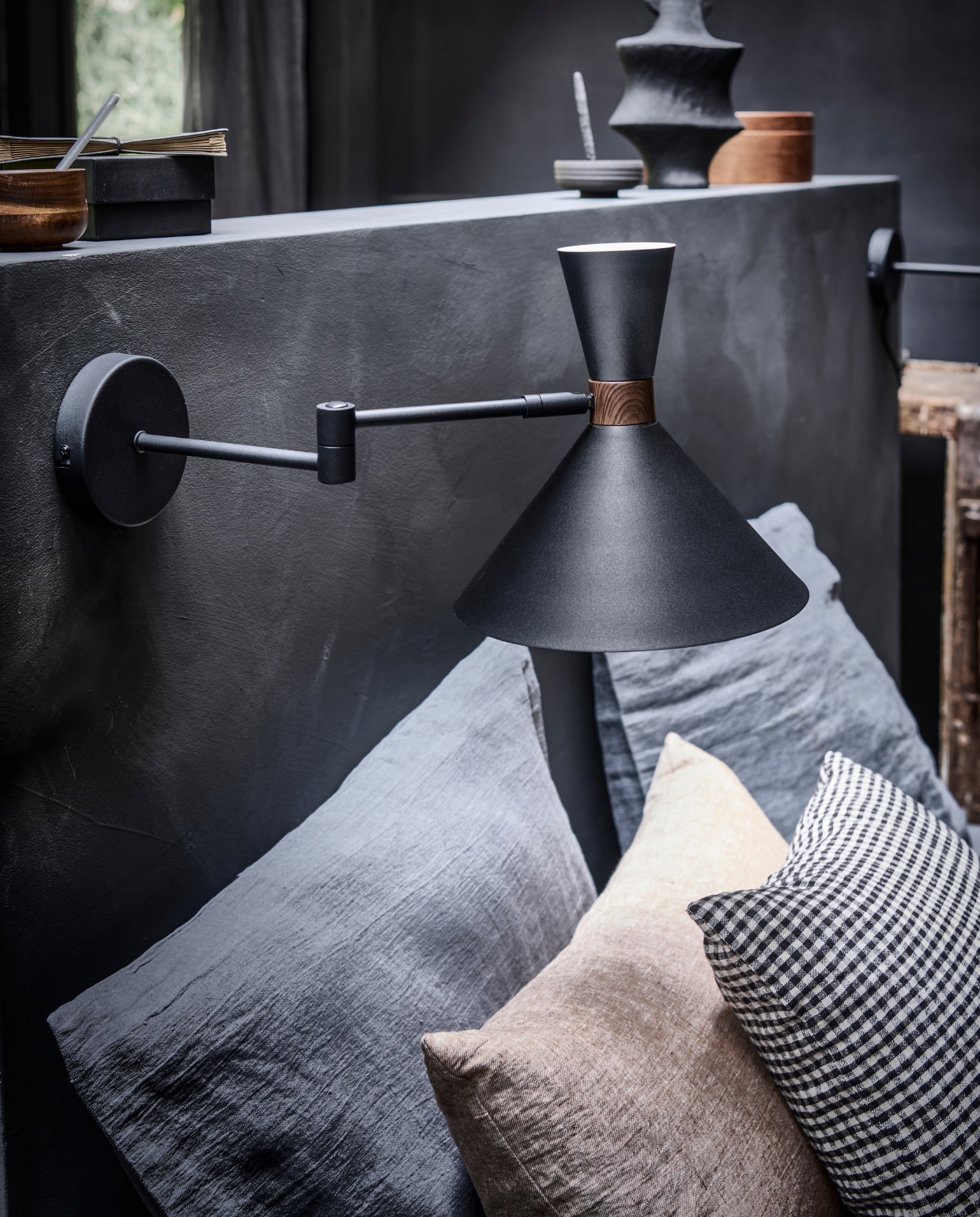 Matzwarte metalen wandlamp Hoodies, 25x25x50,5 cm (lxbxh) € 89,95 (ook verkrijgbaar in zandgrijs).M.m.v. bymolle.com (linnen kussensloop in kleur Slate), paviljoennoord.com (zwart-wit geruit kussen), letoile.store (beige linnen kussen). vtwonen 10-2022 | productie Tanja Saarberg | styling Danielle Verheul | fotografie Sjoerd Eickmans