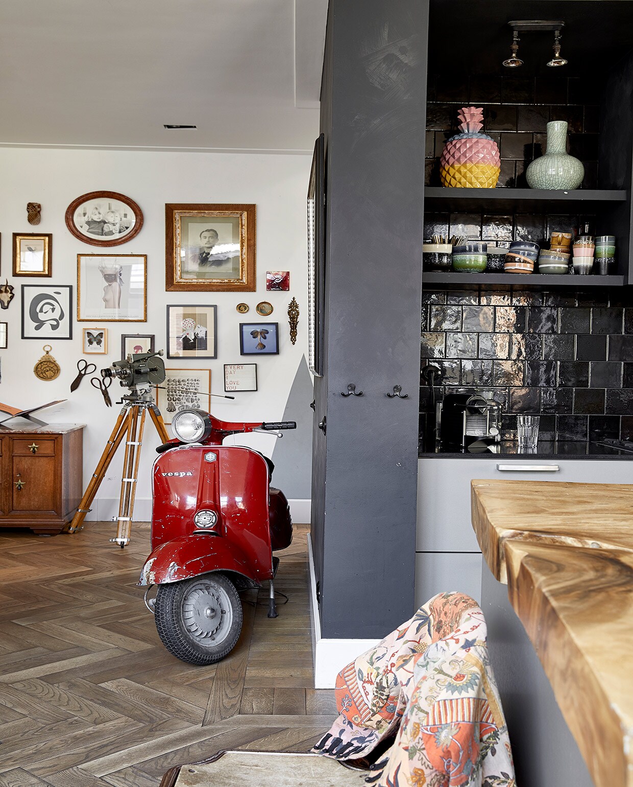 Muurverf Leliewit van Histor en Graphite van CarteColori. Vloer groothandel. Scooter gekregen van Richards vader. Kast Van Dijk &amp; Ko, boekenstandaard Mendo. Camera boedelverkoop. Aan de muur v.l.n.r. Ananas Anna+Nina. Schilderij met vogel Venduhuis de Eland. Ronde lijst Amsterdam Yard Sale. Ingelijste foto uit boedelverkoop. Rode tegel tweedehands. Zwart-wit schilderij Cate Adriana. Ingelijste poster Inez &amp; Vinoodh via Moam. Schilderij op karton Kunsthaus Tacheles. Ronde werken erfstukken. Blauw werk zeemeermin gekocht van bovenbuurvrouw. Kandelaar kringloop. Zonnewijzer gekocht in Marokko. Lijst met vlinder Stenelux. Scharen boedelverkoop. Werk David Bowie Moma Londen. Print schelpen gekregen. Print Anna+Nina. Vazen in de keuken Pols Potten. Servies HKliving en vintage. Wandtegels Piet Jonker vtwonen 02-2021 | productie Coco Features | styling Emmy van Dantzig | fotografie Peggy Janssen