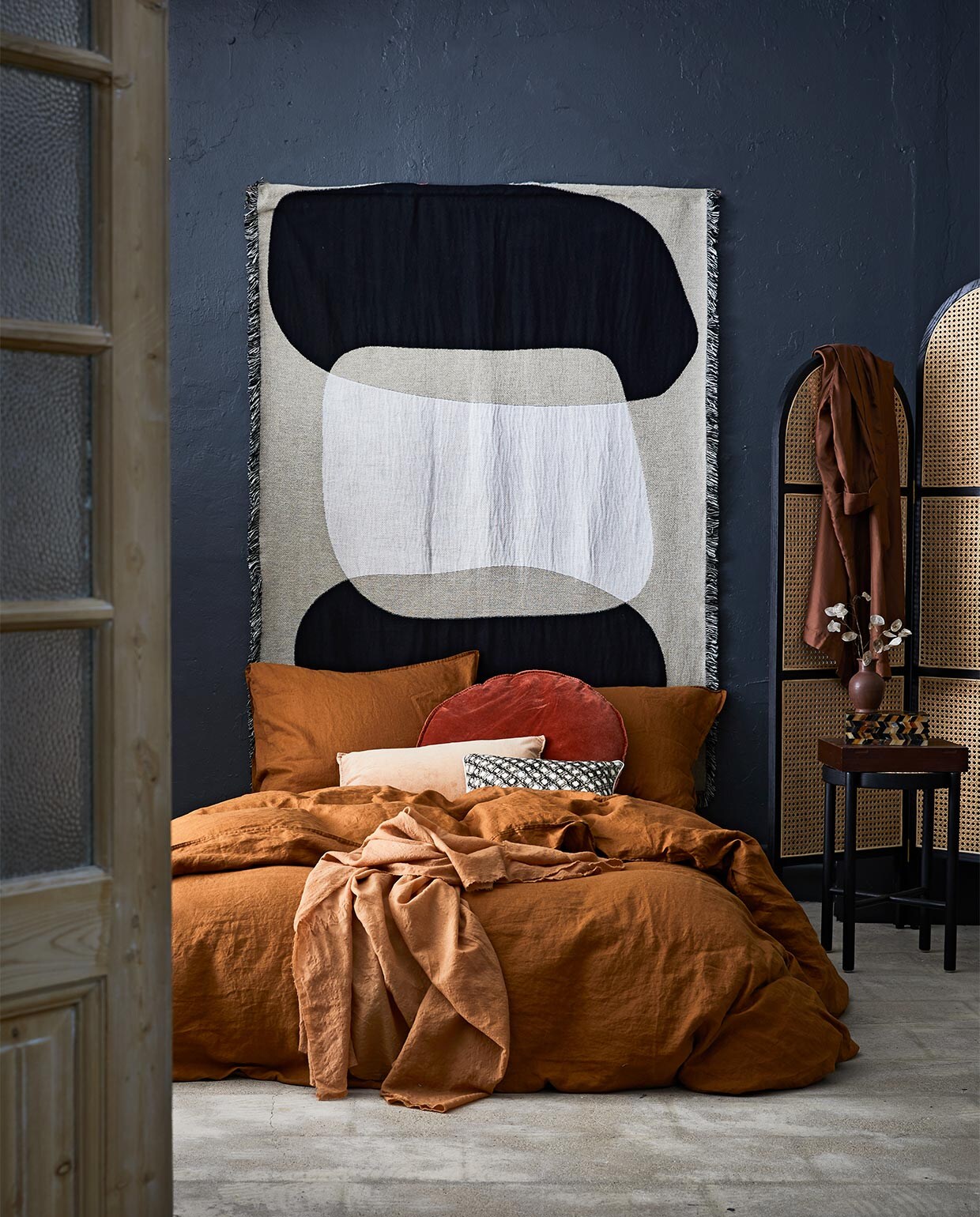 Linnen beddengoed, 220×240 cm € 99,- (H&amp;M). Kussen met dessin van Elitis, 30×60 cm € 125,- (Brecht Murré Atelier). Wandkleed Kanza, 193×145 cm € 230,- (Somée).Fluwelen kussen 40×60 cm € 37,95, rond fluwelen kussen, Ø 60 cm € 69,95, zwart krukje € 129,-, kamerscherm € 449,- (HK Living). Zalmkleurige sjaal € 199,- (Atelier Sukha). Roestkleurig vaasje € 19,95, ingelegd hoornen doosje € 75,-(MaisonNL). Zijden jas privébezit. vtwonen 09-2018 | styling Cleo Scheulderman | fotografie Jeroen van der Spek