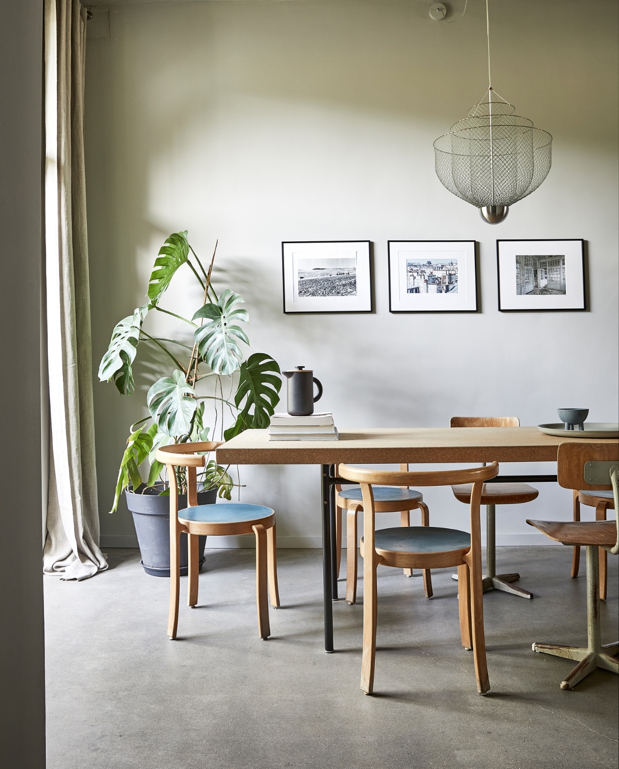 Linnen gordijnen zelfgemaakt. Eettafel Sinnerlig Ikea. Vintage Deense stoelen gekregen, vintage schoolstoelen gevonden in een loods in Drenthe. Cafetière Theo Stelton. Schaaltje Duck Bowl 101 Copenhagen. Platte schaal Mud Australia. Kroonluchter Meshmatics Rick Tegelaar. Reisfoto’s in lijsten van Ikea. vtwonen  binnenkijken special 03-2022 | productie &amp; styling José Martens | fotografie Peggy Janssen