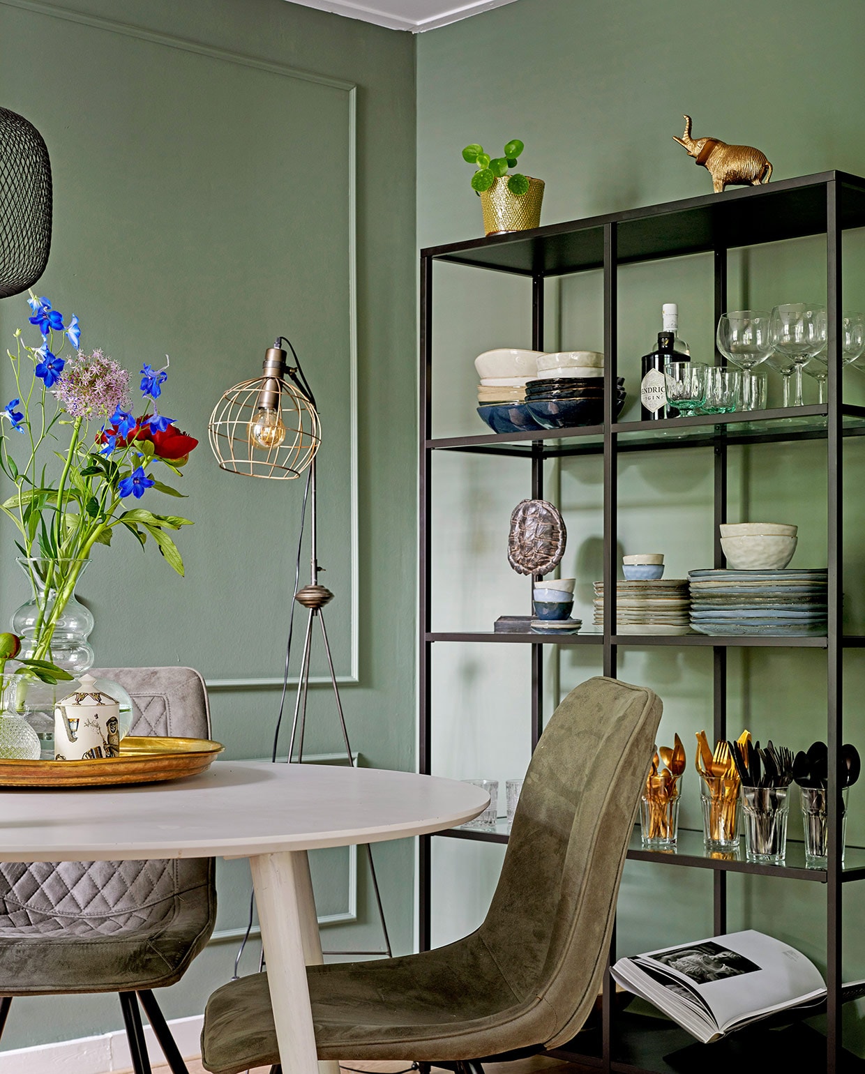 Tafel Made. Stoelen Zitmaxx. Hanglamp Ikea. Dienblad op tafel herkomst onbekend, geurkaars in potje Fornasetti, glazen vaas Living-in By Romy’s. Staande lamp Karwei. Stellingkast Ikea. Plantenpot De Bloemerije. Olifantenbeeldje en goudkleurig bestek Action. Servies Casa. Schildpaddenschild Living-in By Romy’s. vtwonen special tiny houses  03-2021 | productie Features &amp; More  | styling Wilma Custers | fotografie Renee Frinking