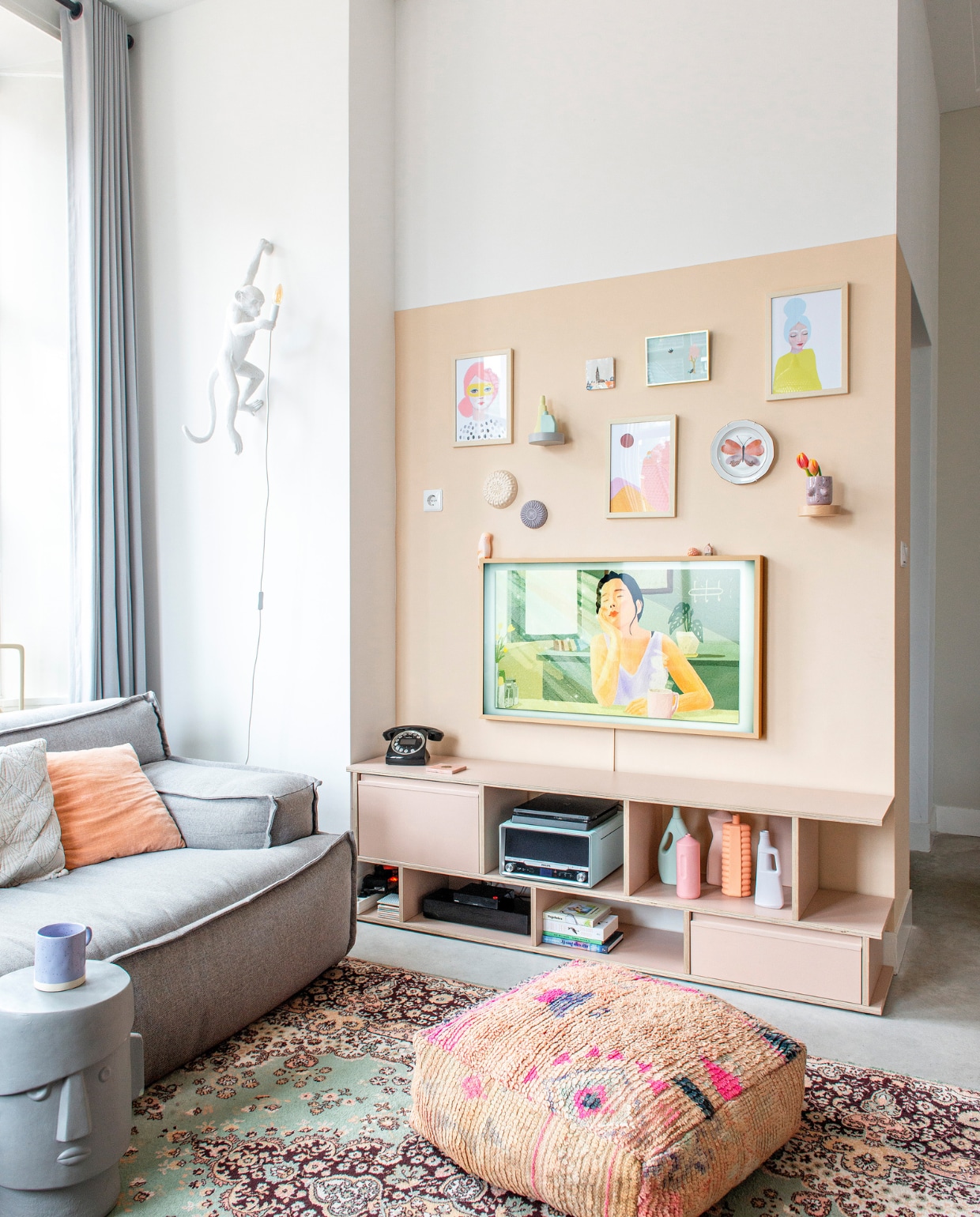 Bank Trendhopper. Televisiekast op maat Tylko. Televisie The Frame van Samsung, telefoon Sage, pick-up Philips. Poef Studio Pure. Kruk Donny van Coco Maison. Vloerkleed vintage. Wandlamp Monkey van Seletti. Kussens Loods 5 en H&amp;M Home. Wandplankjes Ikea. Posters landschap en vrouwen Piet en Kees. Blauwe poster Flow magazine. Wandborden Atelier W, wandbord vlinder Liefs Karlijn. Vazen Foekje Fleur. Tegel Storytiles. Mok Monki. Parkiet Pete Cromer via Prchtg. Huisje vakantiesouvenir. Muurverf Café Latte van Flexa. Betonvloer. Overig onbekend. vtwonen 08-2022 | productie De Binnenkijkers | styling Jeske Weel | fotografie Caroline Coehorst