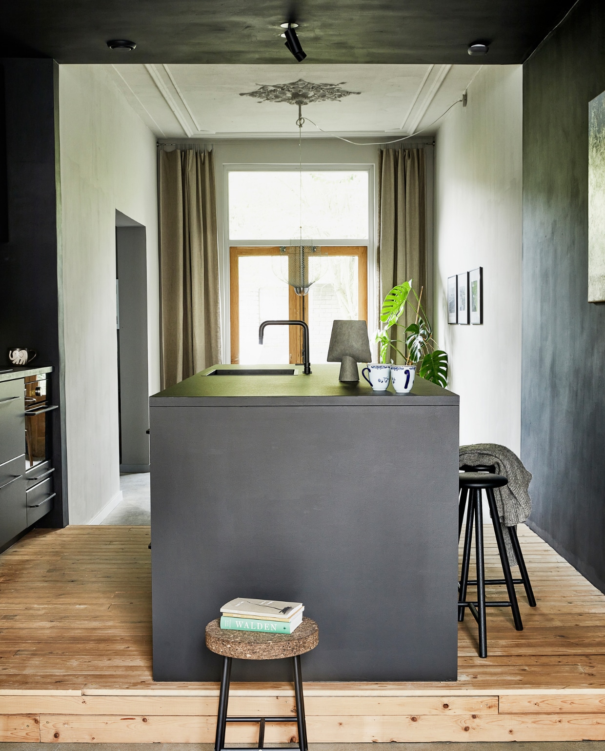 Verfkleur achterkamer Pavilion Gray en keuken Pitch Black van Farrow &amp; Ball. Plafondspot C1B Nosta Victor. Keuken en apparatuur Ikea (fronten Kungsbacka, grepen Borghamn). Werkblad bekleed met Desktop Linoleum Forbo. Kraan Nivito. Vaas Sphere Vase Square 101 Copenhagen. Kopjes Ostindia Rörstrand erfstuk. Barkruk Perch Nikari. Krukje Sinnerlig Ikea. Oude vloerdelen van Destijdsch. vtwonen special binnenkijken 2022-3 | productie en styling José Martens | fotografie Peggy Janssen