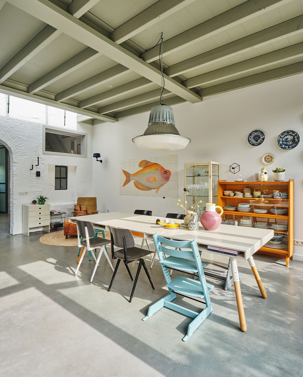 Verfkleur plafond Sikkens H2.05.65. Eettafel Phill Spectrum. Stoelen S16 Galvanitas. Kinderstoelen Tripp Trapp Stokke. Blauwe kruk Tolix. Peper-en-zoutstel Lego. Gele kandelaar Arian Brekveld voor Imperfect Design. Roze bolvaas Ypperlig Ikea. Wandkandelaar Frederik Roijé. Wandlamp Bolt Tonone. Wanddecoratie Yellow Fish IXXI. Vloerkleed Kwantum. Kasten, lectuurtafel, Martin Visser-fauteuil, voetenbank, hanglamp en verzameling wandborden vintage. vtwonen binnenkijken special 131-2022 | fotografie Rene van der Hulst | styling Marloes Wolfs