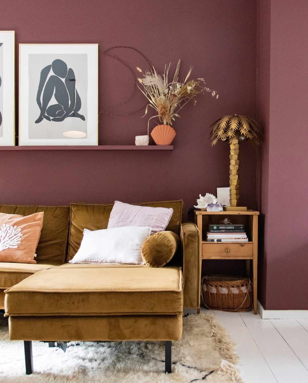 Muurverf Merlot Mania no. 123 Powderbox van Vestingh. Bank Rodeo van BePureHome, linnen kussenhoes H&amp;M Home, rode kussenhoes met schelp À La, koraalkleurige kussenhoes Leen Bakker, vloerkleed Beni Ouarain Outlet. Wandplank Ikea, maan zelfgemaakt, schelp Fonq, bloemen Happy Circle, palmboom HKliving, waxinelichthouder The Spirit Junkies, bijzettafel en mand vintage. Overig onbekend. vtwonen 08-2022 | productie en fotografie Anne den Haan | styling Luka Jakobs