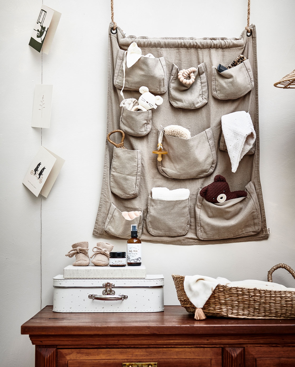 Houten kast € 350,- (vandijkenko.nl). Wall pocket beige van Numero 74 € 59,- (lidor.nl). Verschoonmand zeegras van Cam Cam € 69,95, knuffelkussen zwaan Vicky Swan van Numero 74 € 64,- donkerbruine knuffelbeer Bernard van Bonton € 24,-, houten borstel in vorm van schelp van Konges Sløjd, set van 3 € 40,- (storeofdaydreams.com). Kartonnen koffer met stippen € 15,99, muizenrammelaar € 17,99, mousseline slinger € 17,99, mousseline handdoek € 9,99, rotan rammelaar € 15,99, rotan plafondlamp € 69,99, beige kam met schildpadmotief € 11,99 (zarahome.com). Speendoek in maan-vorm van Dappermaentje € 23,95, slofjes van Hvid € 34,95 (psikhouvanjou.nl). Fopspeen € 4,95 (dekleineparade.com). Babyverzorging van Alma vanaf € 35,-, baby book € 49,95, hoornen kam van Atelier Annur € 21,95, siliconen bijtring van Little Chew € 19,95 (zoenvoorgust.com). Kaartjes vanaf € 1,50 (keizerin.nl). vtwonen 13-2021 kids special | styling Kim van Rossenberg | fotografie Sjoerd Eickmans | Assistentie Sanne van der Beek, Judie Jonker, Kim Suos\n