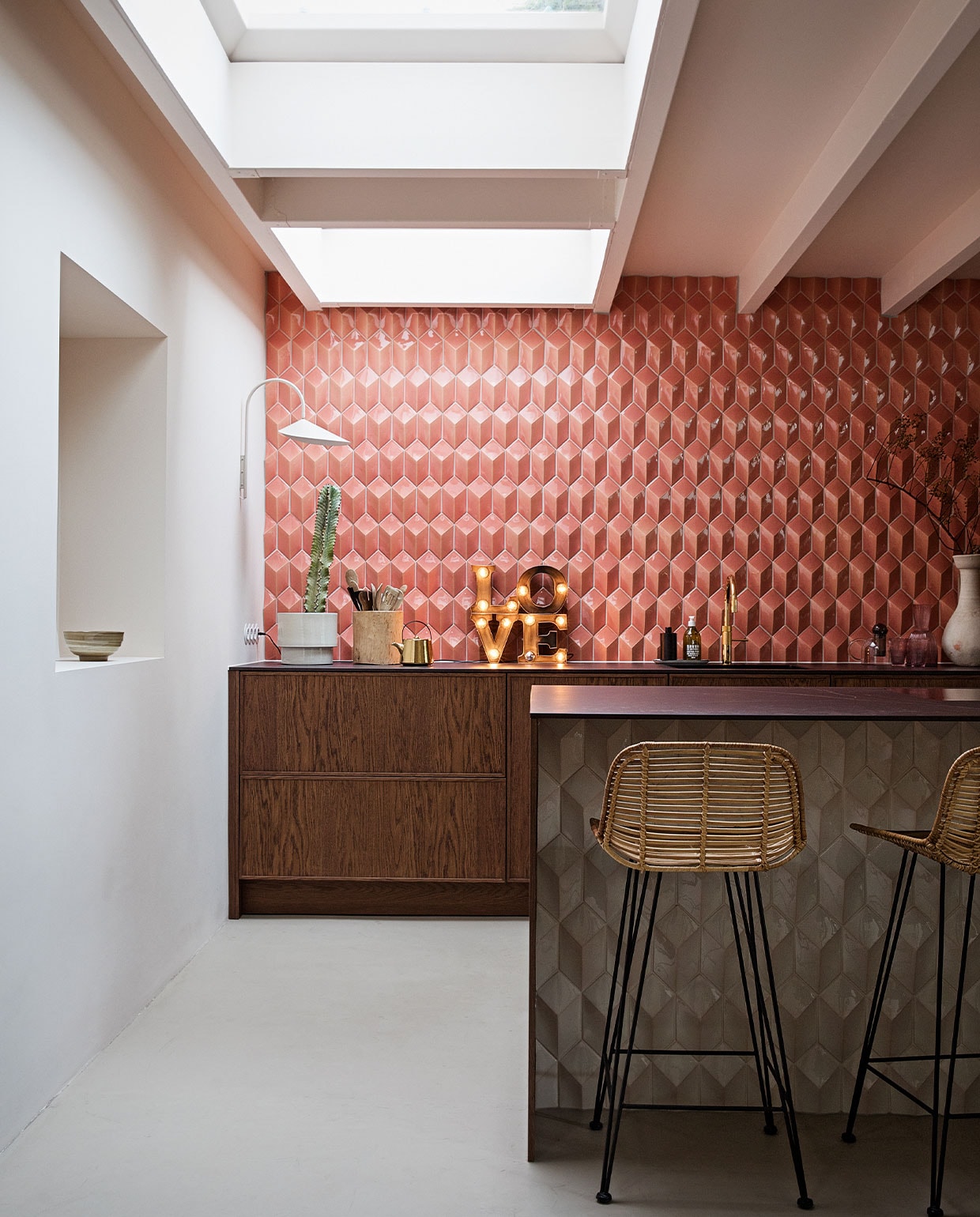 Barkrukken, theepot en kom in nis HKliving. Wandlamp Ferm Living. Love lamp Sissy-Boy Homeland. Tegels Constellation kleur Flamingo Baby via Quintalisque. Kraan Quooker. Houten pot Household Hardware. Bloempot H&amp;M Home. Planten Blóm. Overig herkomst onbekend. vtwonen 02-2022 | styling Ilona Jongepier | fotografie Dana van Leeuwen | tekst Martine de Hoog