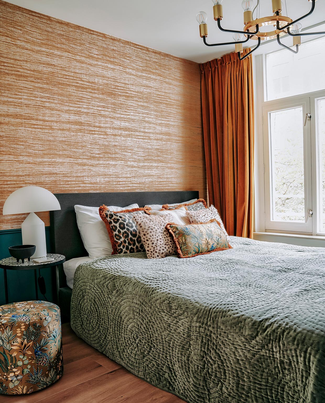 Poef, bijzettafel, schaaltje, kussens en sprei Nox Studio Interiors. Witte lamp Oluce, hanglamp Westwing. Verf op lambrisering Inchyra Blue van Farrow &amp; Ball, behang Arte. Bed Wehkamp, hoofd-kussens Hema, gordijnen Dappermarkt. vtwonen 06-2021 | Productie CocoFeatures | Fotografie Muk van Lil | tekst Cathelijne van Wingerden