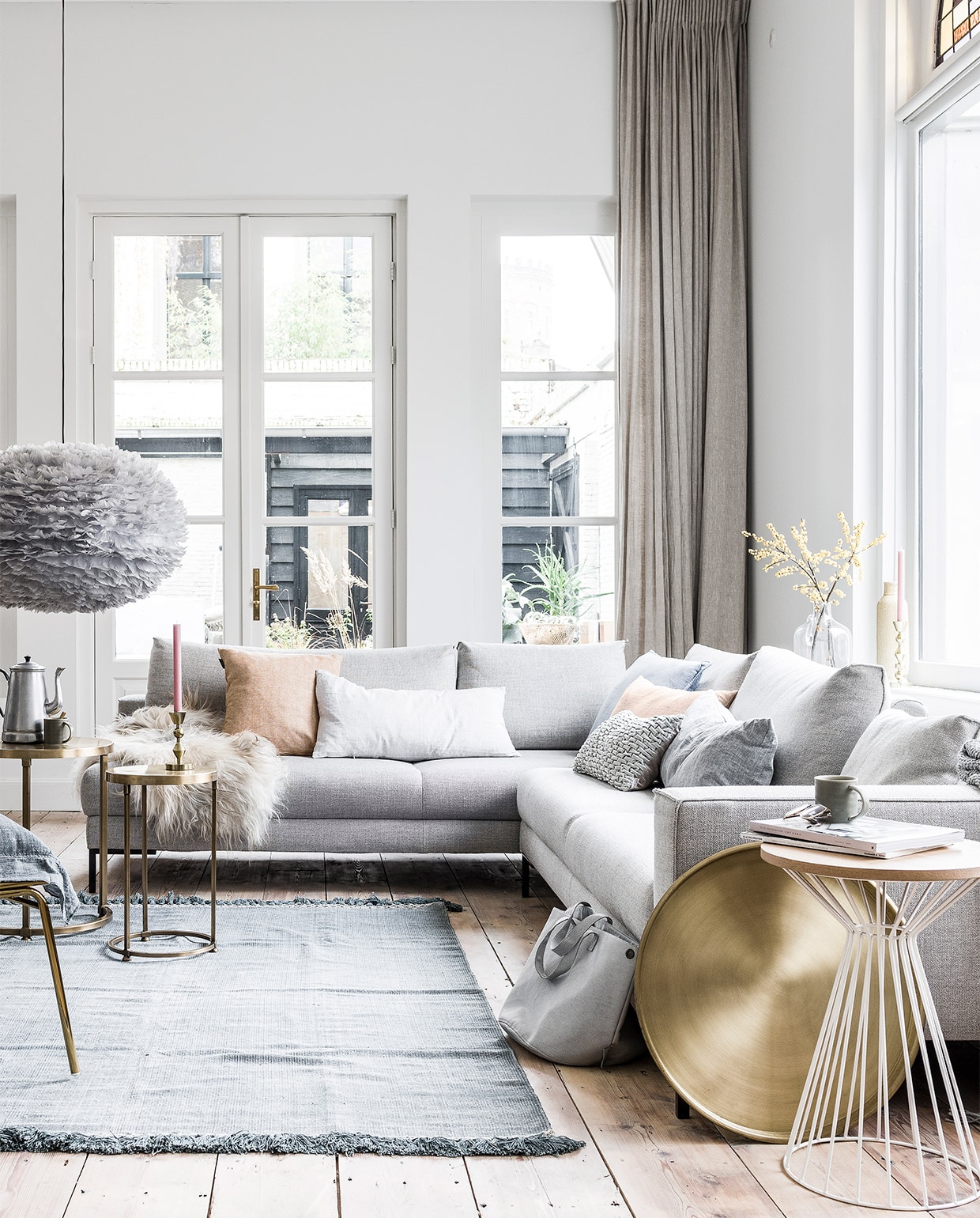 Hoekbank Aikon Lounge van Designonstock 2x 62x246x102 cm (hxbxd) € 3298,-, wit draadwerk tafeltje € 159,- (Eijerkamp). Schapenvacht krul € 99,- (Het Kabinet). Linnen kussens in zachte pastellen van By Mölle € 69,95, goudkleurige draadwerk loungestoel Mesh van Bloomingville € 469,- (vtwonen.nl). Blauw fluwelen kussen € 19,95 (Goround Interior). Grijs kussentje met lusjes € 24,99, grijze tas van Zuss € 44,95 (Nijhof). Grijze deken met gerstekorreldessin € 49,95, kandelaar groot € 19,99, kandelaar klein € 14,99 (H&amp;M). Brass tafeltjes Alex per set van 2 € 199,-, blauw chambrey kussen van vtwonen, 60×60 cm € 44,95, goudkleurig dienblad Brass € 27,50 (Het Kabinet). Vloerkleed Mekong Nights Stonewash Blue L, 160×230 cm € 229,- (aaimadewithlove.com). Hanglamp Eos van grijze veertjes € 399,-, kopjes per stuk € 7,95 (Nijhof). Lijst met foto van kind gemaakt door fotografe Linelle Deunk. Koffiekan en glazen vaas privébezit. JA | vtwonen 03-2017 | styling Moniek Visser  | fotografie Sjoerd Eickmans
