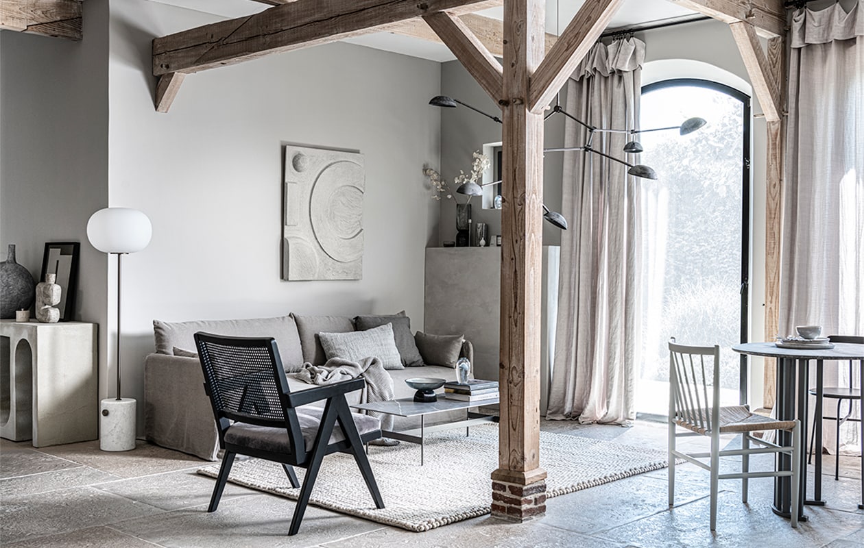 Op de wand kalkverf Old Flax van Pure &amp; Original, 1 liter € 40,75 (pure-original.nl). Vloerkleed Tararu, 220×300 cm € 9940,-(kristiinalassus.com). Kunstwerk N°05 in kleur Stone, 60×40 cm prijs op aanvraag (atelierledition.com). Percolator Lady Anne € 59,-, tweekleurige keramieken mok Earth € 17,50 (bymolle.com).Bruine mok € 5,90 (letoile.store). Vloerlamp Line One met onbehandelde mat marmeren voet en geoxideerde aluminium kap € 650,- (norr11.com). Bank op maat gemaakt, prijs op aanvraag, kandelaars, 30, 40 en 50 cm (h), set van 3 € 46,-, bijzettafel antiek brons, 36×49 cm (Øxh) € 85,- (stylexclusief.nl). Rechthoekig kussen, 30×50 cm € 7,99, vierkant kussen, 50×50 cm € 35,99 (zarahome.com). Kussen Twine, 40×60 cm € 179,-, fiberglass kuipstoel Eames DAX van Vitra € 750,- (homestede.nl). Grijsblauw gestreept kussen van by Nord € 59,95, gebreide plaid Pien, 130×170 cm € 69,95 (loftloft.nl). JA | vtwonen 11-2021 | styling Kim van Rossenberg  | fotografie Sjoerd Eickmans