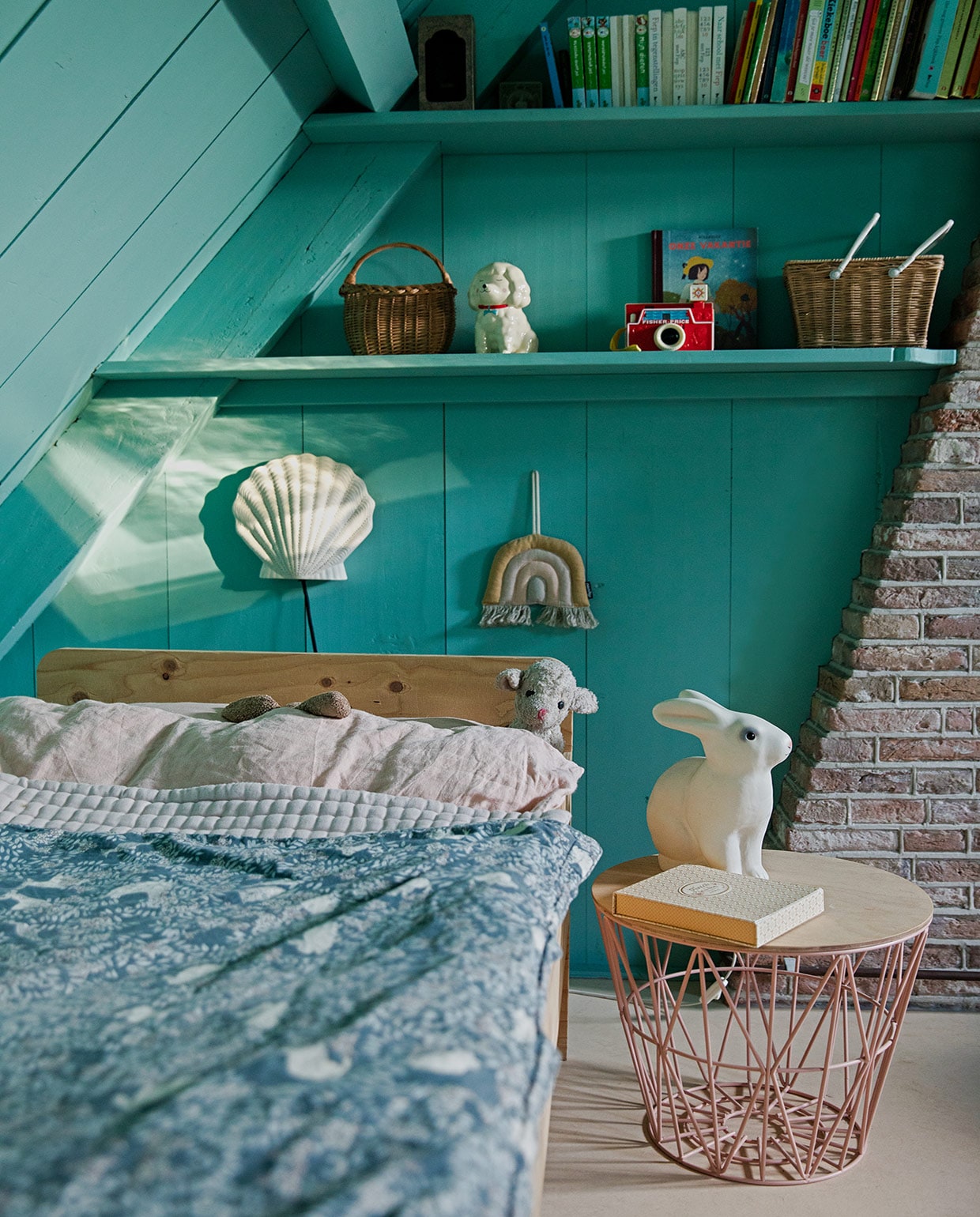 Muurverf Histor Geest van Histor, bed Piet Hein Eek, beddengoed Garbo &amp; Friends, bijzettafel Ferm Living, nachtlamp schelp Little Dreamers, konijnenlamp Heico. Wandhanger Etsy, spaarpot MaisonNL, Fisher-price camera van Roos geweest, mand met witte handvaten Olli Ella, mandje vintage, doosje Maileg, boek Vakantie van Blexbolex. vtwonen 05-2021 | Productie en Styling Ilona Jongepier | Fotografie Dana van Leeuwen | Tekst Anna van der Heijden\n\nvtwonen 05-2021 | kinderkamer met een konijn op het nachtkastje en een regenboog wanddecoratie met wandplanken