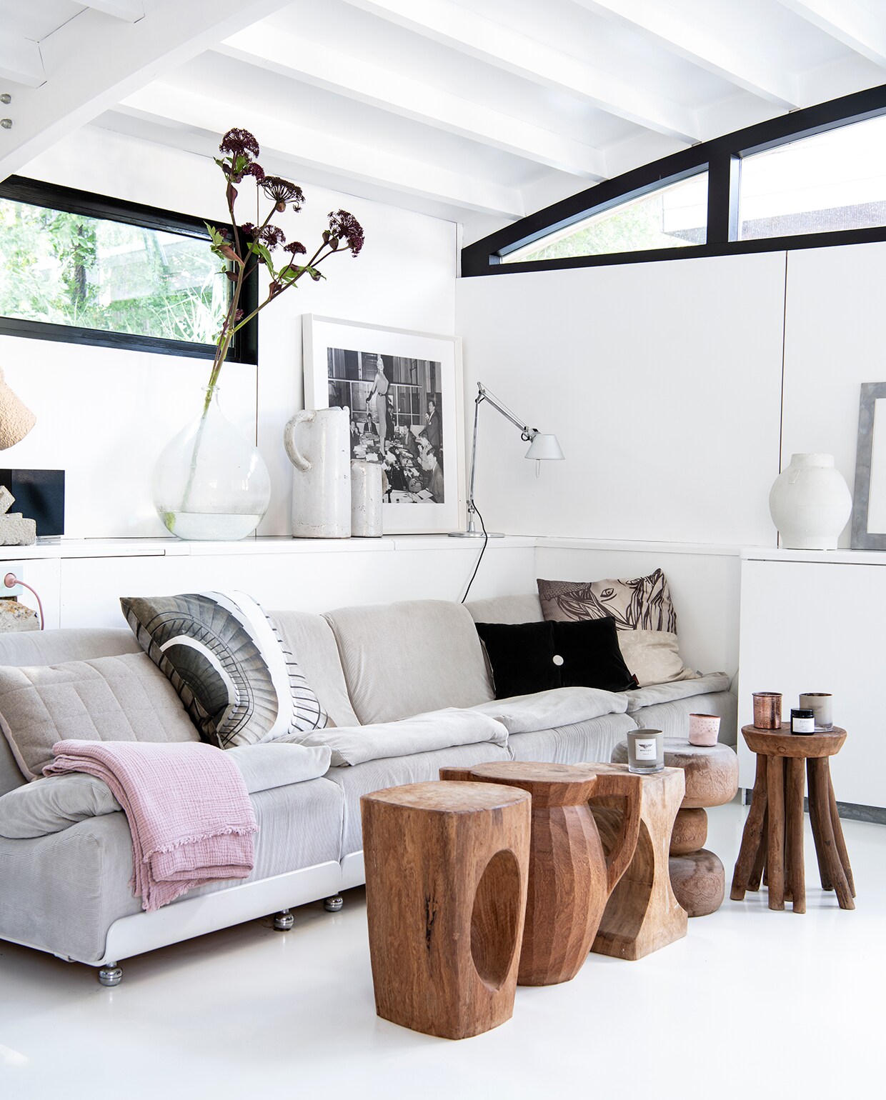 Vintage bank Orbis van Luigi Colani voor Cor, roze plaid Ikea, zwartwit kussen Friday Next (bestaat niet meer), zwart kussen met knoop De Kussenfabriek en crème kussen met print Marcel Wanders voor B&amp;B Italia. Ervoor een verzameling houten bijzetters van Pols Potten via Marktplaats. Erop geurkaarsen in glas, merk onbekend. Achter de bank op de verhoging takken in grote brocante vaas, kannen Sissy-Boy Homeland, ingelijste zwartwit foto van Jayne Mansfield door Ben van Meerendonck. Tafellamp Tolomeo van Artemide, witte vaas Hella Jongerius voor Koninklijke Tichelaar. vtwonen 2020 DIY special 2 | styling Esther Loonstijn | fotografie Louis Lemaire