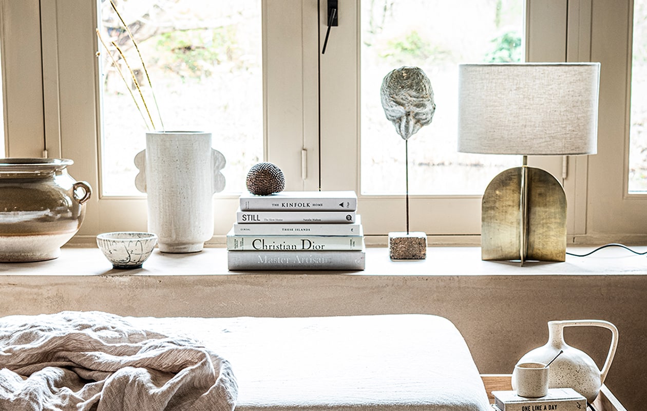 , Witte, gespikkelde vaas van HKliving € 34,95 (vtwonen.nl). Vloerkleed 200×300 cm € 169,-, linnen deken 140×190 cm € 79,99, lamp met goudkleurige metalen voet € 89,99, verwassen linnen onderlaken € 45,99, bruine pot met oortjes € 59,99 (zarahome.com). Beige aardewerken vaas met darius oortjes van Urban Nature Culture € 49,99 (sissy-boy.com). Overig privébezit. JA | vtwonen 04-2021 | styling Kim van Rossenberg  | fotografie Sjoerd Eickmans