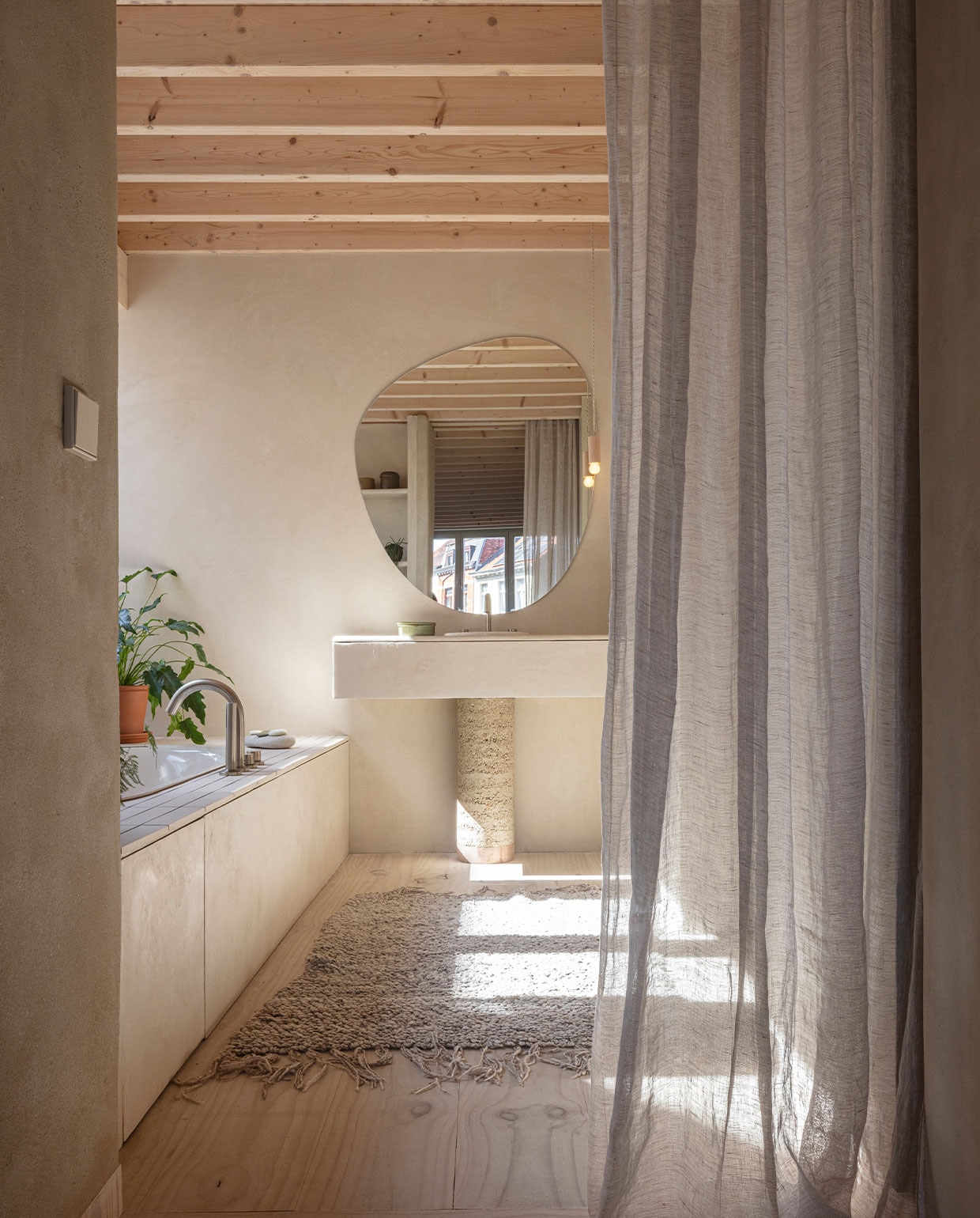 Kranen Crosswater en Wiesbaden. Wasbak Loop &amp; Friends van Villeroy &amp; Boch. Wastafelvoet zelfgemaakt met rammed earth van BC Materials. Spiegel op maat laten snijden. Lamp gemaakt door de vader van Nicolas. Vloerkleed meegenomen uit Marokko. NEE | vtwonen 7-2022 | fotografie Tim Van de Velde | tekst Iris De Feijter | tekstbewerking Chris Muyres