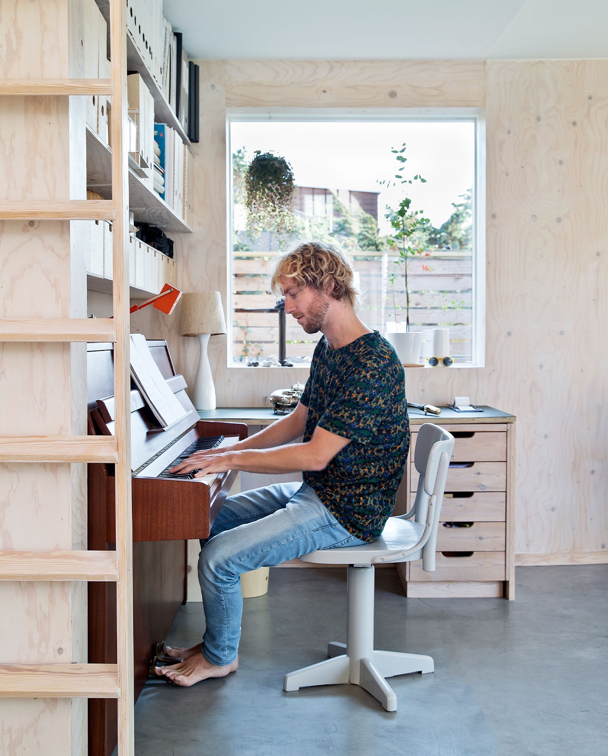Boekenplanken Ikea, piano Yamaha. Stoel, schemerlamp, kandelaar en plantenpotten kringloop. Bureau eigen ontwerp. NEE | vtwonen 7-2022 | Productie Living Inside | Styling Rikke Graff Juel | Fotografie Christina Kayser O. | Tekst Christina B. Kjeldsen | Tekstbewerking Sunna Borghuis
