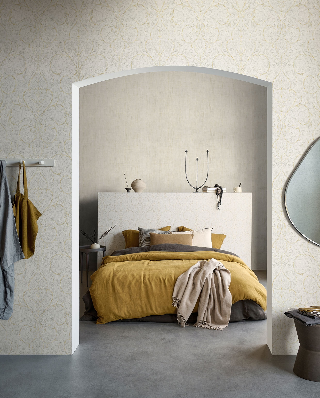 Behang op voorste wand en hoofdbord Classic Curl Light Grey, op achterste wand Linnen Gold, 53 cm breed, rol van 10 meter €29,99 (Classic Curl ook verkrijgbaar in Sea Green).M.m.v. pure-original.nl (muurverf Fresco in kleur Old Flax), paviljoennoord.com (linnen ochtendjas, linnen tas, linnen dekbedovertrekken, linnen kussenslopen, zwart wit geruit kussen, olijfgroen kussen), vtwonen.nl (spiegel van Ferm Living), loods5.nl (stenen kruk, metalen bijzettafel), letoile.store (keramieken vaasje, wierookhouder, mok), hm.com (gedraaide vaas), sissy-boy.com (metalen kandelaar, plaid), zarahome.com (wit kussen). Overig privébezit. vtwonen 06-2022 | productie Tanja Saarberg | styling Danielle Verheul | fotografie Sjoerd Eickmans | assistentie Kula van den Broek