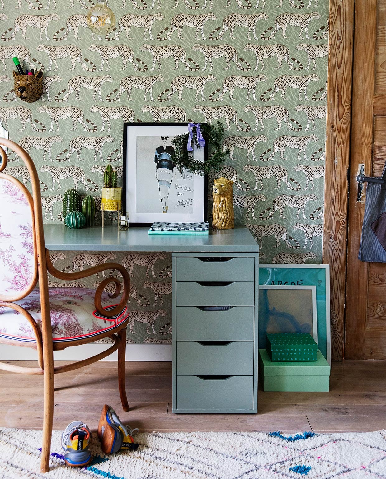 Behang Leopard Walk 109/2009 Cole &amp; Son, bureau zelfgemaakt en -geschilderd met blad van bouwmarkt en ladekastjes van Ikea, stoel Thonet Marktplaats, vloerkleed Living Maroc, panterkop Homestock, hanglamp Calex, cactussen Ikea, geel potje op pootjes cadeau gekregen, plakbandhouder Hema, groene dozen op grond, fotolijsten en poster zwart-wit Ikea, posters vloer dolfijn door Run Jie geschilderd. JA | vtwonen 12-2020 | styling Ilona Jongepier  |  fotografie Dana van Leeuwen | Woning van hoofdredacteur Nicolette Fox