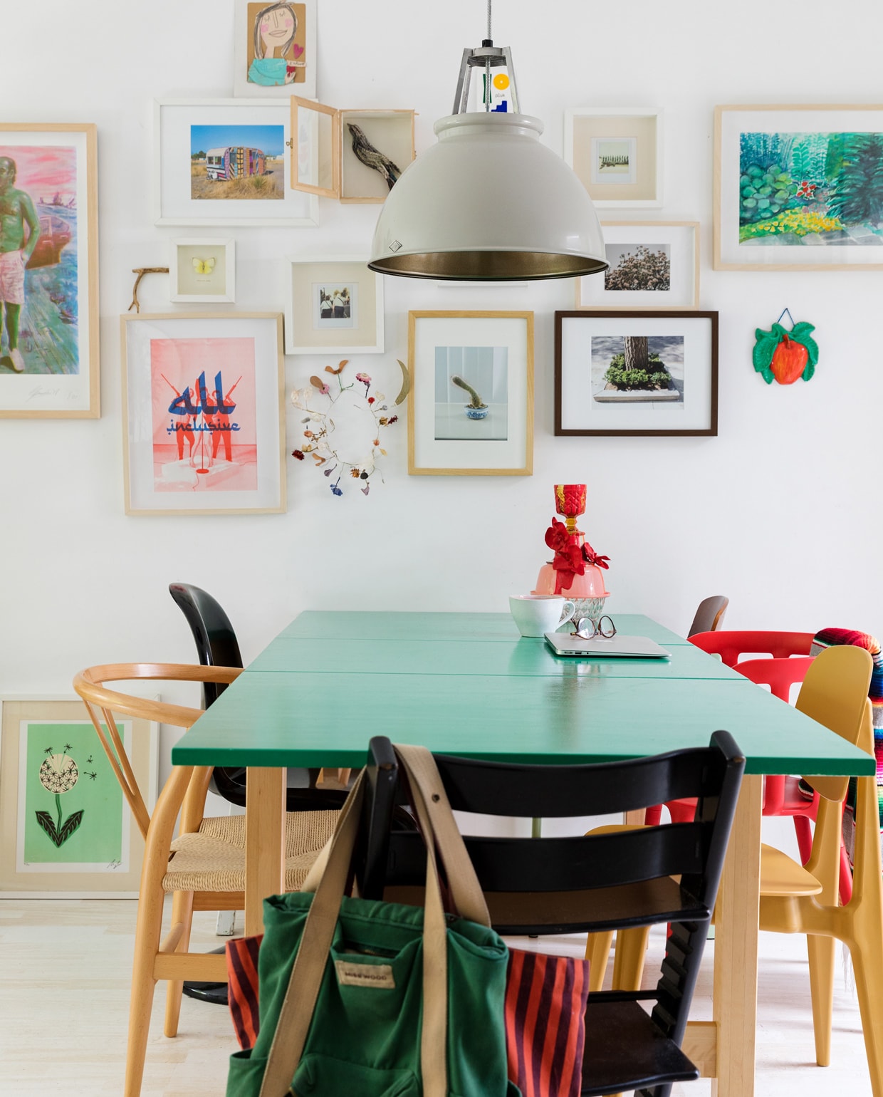 Tafel Ikea. Muurverf Tijdloos Hoogglans Gamma. Lamp Original BTC. Stoelen: rood Ikea, geel Loods 5, zwart de Tripp Trapp stoel van Stokke en een kopie van de Panton Chair van Vitra, hout een kopie van Carl Hansens Wishbone Chair. Mexicaanse plaid Tica. Groene rugtas Miss Wood. Rood gestreepte tas Sissy-Boy. Vaas Vazen van Janssen. Mok Xenos. Lijsten: Vogel van Elke Lutgerink. Zeefdruk man met roze broek Gies Backes. Appel-hanger en geschilderde tuin van de kringloop. Foto’s Maarten Kuypers. Gehaakte caravan gekocht in een gallery in New York. Plantaardige kroon Loesje van Herp. Riso print All Inclusive Julian Hetzel. Meisje van karton Anna Llenas. Paardenbloem zeefdruk herkomst onbekend. Foto bloesem Lineke Theelen. Gele vlinder gekregen van een vriendin. vtwonen 13-2021 | styling Ilona Jongepier | fotografie Dana van Leeuwen | haar &amp; make-up Djolien de Kreij | tekst Eveline Stoel