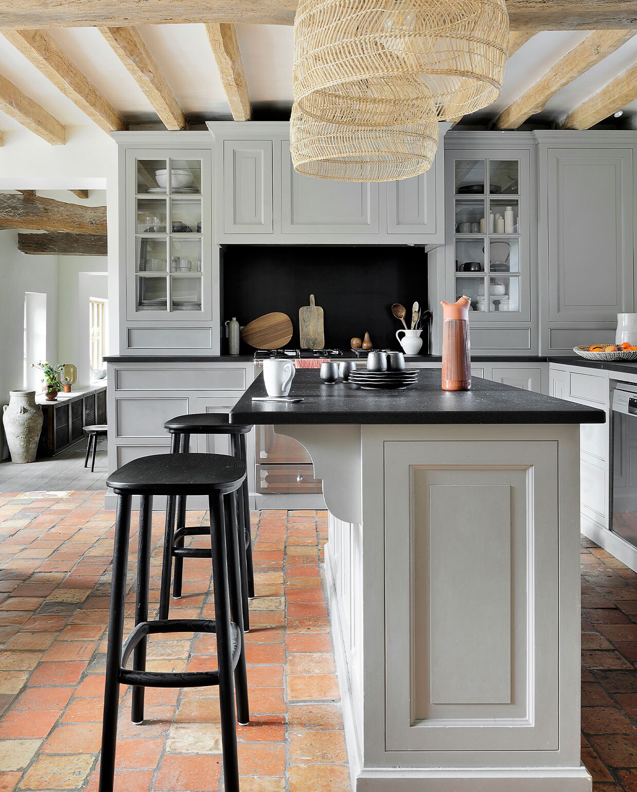 Keuken op maat gemaakt met granieten blad en geverfd in Manor House Gray van Farrow &amp; Ball. Lampen Ball HKliving. Krukken Paddle Cruso. Zwart servies 101 Copenhagen. Karaf Junto Normann Copenhagen. Kruik van Belgische rommelmarkt. Tafellamp Frandsen. Overig onbekend. vtwonen special binnenkijken 03-2022 | fotografie Frenchie Cristogaton
