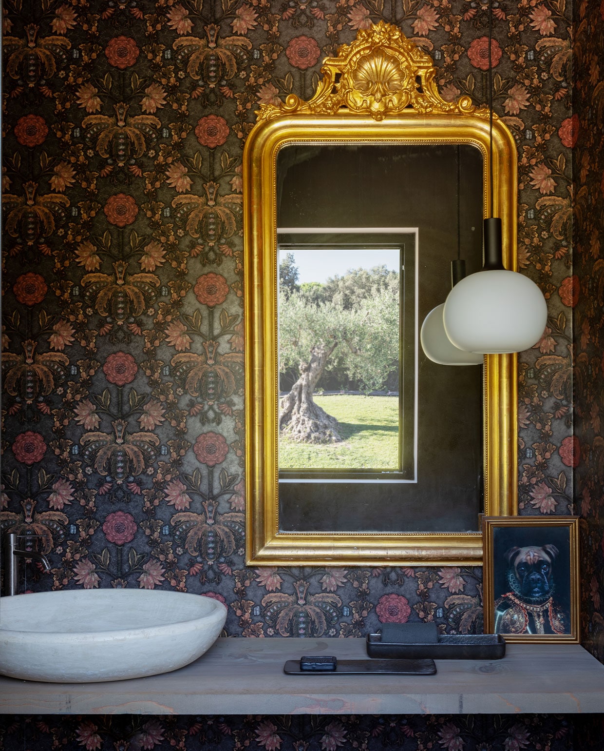 Antieke spiegel gekocht in Italië. Behang Cole &amp; Son. Cederhouten plank als wastafelmeubel, wasbak gemaakt uit travertin. vtwonen 07-2023 | productie Living Inside | fotografie Monica Spezia