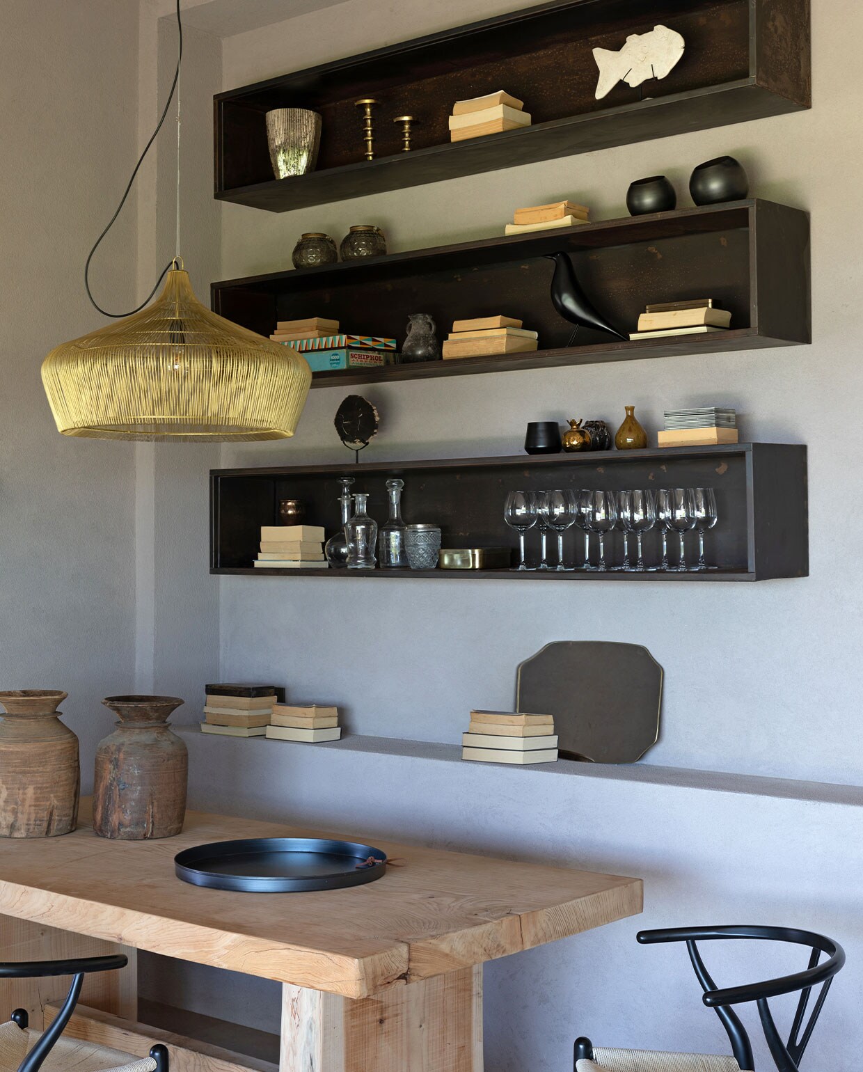 Cederhouten eettafel en zwartmetalen wandkasten ontworpen door Hanne Poli. Vintage Y-chairs van Hans J. Wegner. Koperen hanglamp Haans Lifestyle. Vazen meegenomen van reizen. House Bird van Vitra. Overig onbekend. vtwonen 07-2023 | productie Living Inside | fotografie Monica Spezia