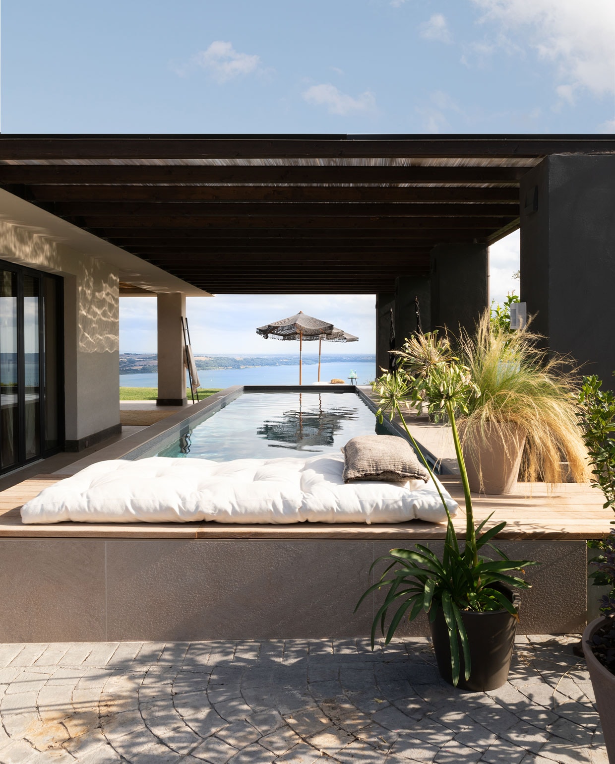 Relaxplek bij het zoutwaterzwembad met het spectaculaire uitzicht op Lago di Bracciano. vtwonen 7-2022 | productie Living Inside | fotografie Monica Spezia