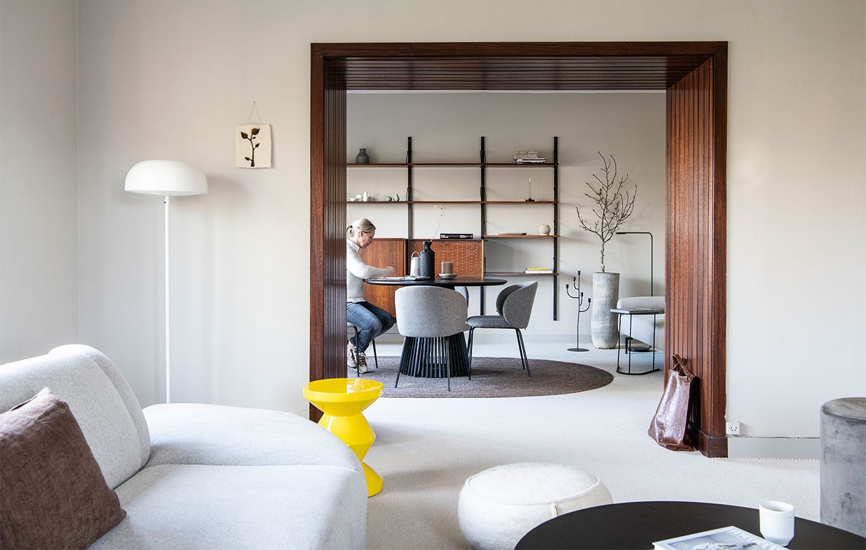 Muurverf Sikkens in RAL7044, mat. BankHKliving. Kussen Tell me more van Jet At Home. Witte poef Jacobien Life & Style. Salontafel K’willeminhuis, stenen bakje en kaars Anne-Marie Wonen. Kunstwerkje Tiny Stories. Witte en zwarte vloerlampen Ikea. Gele kruk Zig Zag van Pols Potten.Zwarte eettafel Goossens Wonen. Zwarte vaas vtwonen. Muziekbox Bose. Stoelen Svenlars. Vloerkleed House Doctor. Vintage wandrek Meubelfabriek LOV Oosterbeek. In wandrek, van links naar rechts en boven naar beneden: vaas Urban Nature Culture, gerafeld notitieboek Lamali Paris Paper Booklet van Nomad Paulette, witte vazen Studio Peetlein, grijze vazen Lindform via Anne-Marie Wonen, boek Peter Lindbergh, ovale, marmeren schaal en witte vaas Anne-Marie Wonen.Kandelaar en bijzettafel K’willeminhuis. Tas Bea Mombaers for Serax via So Pure Store. Overig onbekend. vtwonen binnenkijk special 121-2021 | productie Insidehomepage | styling Esther Loonstijn | fotografie Louis Lemaire