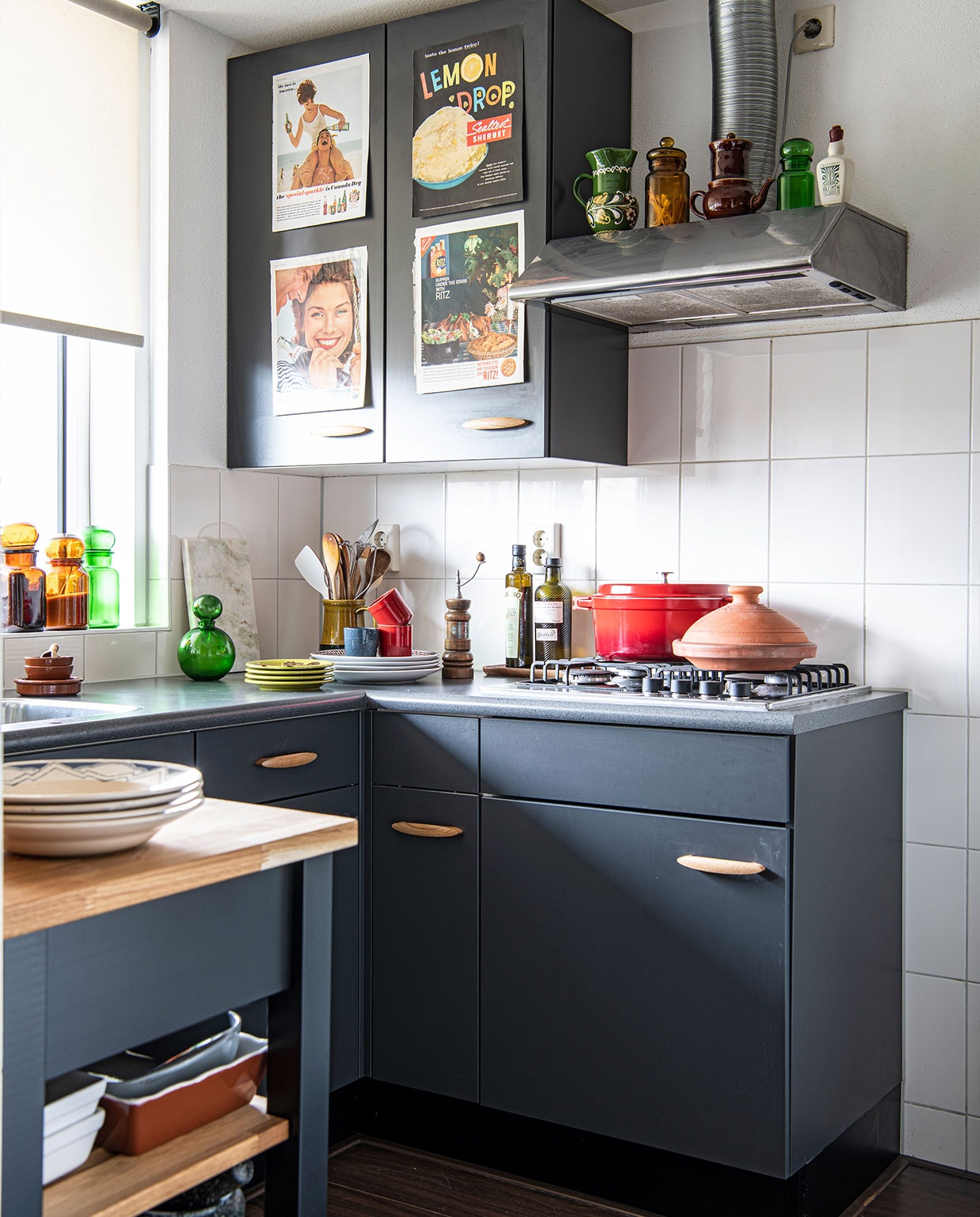 Rode pan Le Creuset, tajine, borden en bruine kommen Dille &amp; Kamille, pepermolen erfstuk, rode espressokoppen H&amp;M Home, kan met lepels vintage. Marmeren plank Flying Tiger, groene kan vintage, groene en bruine kannen in raam tweedehands winkel, borden met blauw antiekwinkel Hans te Kloese. Op de afzuigkap groene vaas, bruine kan en groene kan tweedehands winkel, bruine theepot erfstuk, witte Absinth fles, prints op keukenkasten uit Amerikaanse tijdschriften. Overig onbekend. NEE | vtwonen 6-2022 productie Insidehomepage | styling Kim Timmerman | fotografie Louis Lemaire  | tekst Anne-Flore Muller