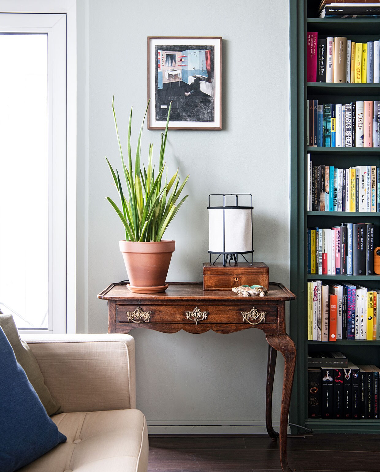 Vloer Ikea, muurverf Mizzle van Farrow &amp; Ball. Eettafel en oranje stoel cadeau gekregen, eettafelstoelen en hanglamp Gispen. Planttafel Marktplaats, vloerkleed Zara Home, televisiekast zelfgemaakt, fauteuil Rob Parry via Marktplaats. Kunst van links naar rechts Daniela Schwabe, Maze de Boer, Luis Xertu. Overig onbekend. NEE | vtwonen 6-2022 productie Insidehomepage | styling Kim Timmerman | fotografie Louis Lemaire  | tekst Anne-Flore Muller