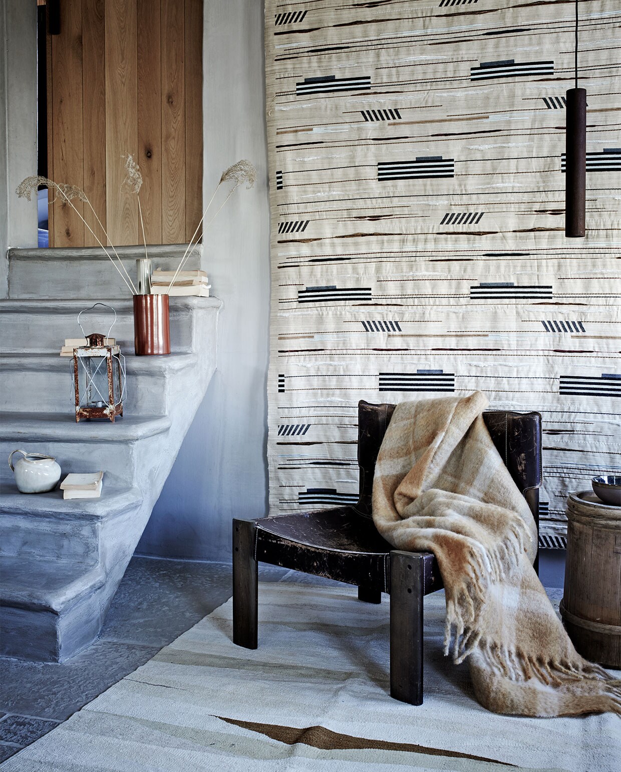 Stof wandkleed Pelops Gris Ombre van Nobilis, vloerkleed Vegetal Natural Stripes van Golran- (wva.nl). Vintage leren fauteuil- (pietjonker.nl). Mohair deken met ruit (zarahome.com). Kan, ecru vaas, schaaltje, alles van Serax (vtwonen.nl). Windlicht (com-anders.nl). Rode cilindervaas (klevering.nl). Houten bijzettafel (burbri.nl). Overig privébezit. JA | vtwonen 11-2019 | styling Danielle Verheul | fotografie Petra Steenkamer