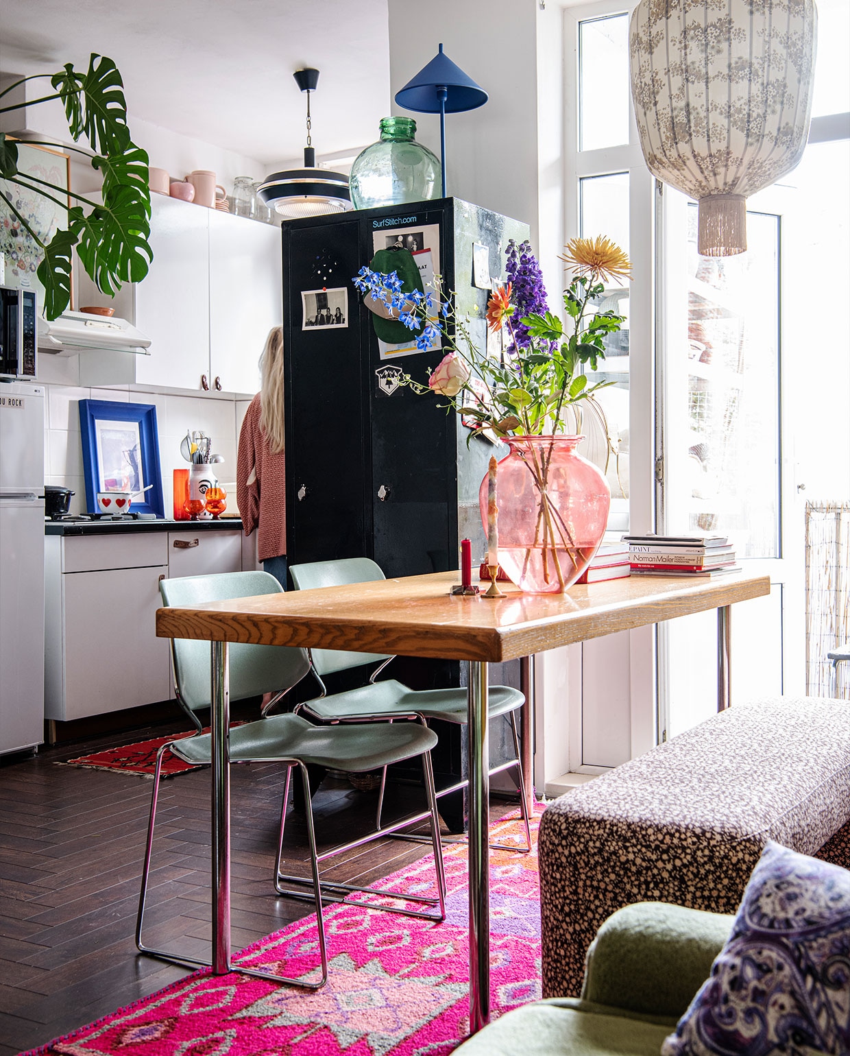 Kussens, roze tapijt en bankje Doris voor HKliving. Blauwe lamp op kast, oranje glaswerk en rood vloerkleed keuken HKliving. Hanglampen Vintage Depot. Leren handvatten keukenkasten zelfgemaakt van leren riem. Pot Pols Potten. Blauwe lijst Ikea. Steelpan erfstuk. Roze servies op de keukenkasten Nørd conceptstore. vtwonen 02-2022 | productie Insidehomepage | styling Kim Timmerman | fotografie Louis Lemaire