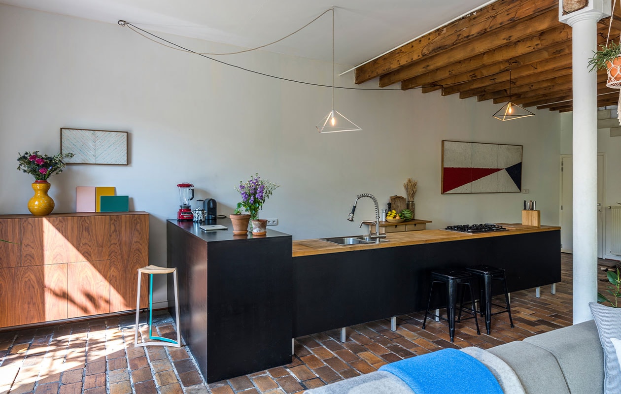 Kast Pastoe, vaas en schilderijen Russell Scarpulla. Stoel en lampen HateLove Maria Scarpulla. Zwarte krukken Tolix van Xavier Pauchard. Dekens ZigZagZurich. vtwonen 6-2022 | Productie Living Inside | Fotografie Luc Roymans | Tekst Mirjam Rosema-Verhulst