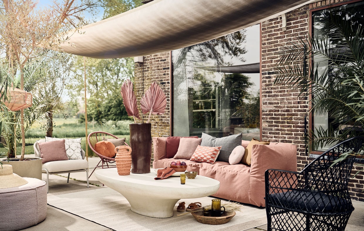 Schaduwdoek gemaakt van buitenstof Padua van Designers Guild, per meter € 73,-, wit rechthoekig buitenkussen met ikat print € 70,- (wva.nl). Buitenpoef vanaf € 525,-, zachtgrijze fauteuil met witte zitting € 2620,-, terra vierkante tuinkussens, per stuk € 151,-, terra langwerpig tuinkussen € 151,-, zachtroze rond tuinkussen vanaf € 410,- (dacks.nl). Hoed € 39,99 (zarahome.com). Rotan windlicht € 39,99, terracotta schaal, 20 cm (Ø) € 29,99, suède sandalen € 79,99 (sissy-boy.com). Betonnen bloempot vanaf € 150,- (nordal.eu). Buitenkleed van Lafuma, 200×290 cm € 269,90, oranje rond buitenkussen van Hartman € 24,95, buitenkussen met oranje retro dessin van Hartman € 29,95 (vtwonen.nl). Bruine tadelakt vaas € 115,- terracotta vaas, 35 cm (h) € 85,-, witte saladeschaal, terracotta met tadelakt finish, 38 cm (Ø) € 47,50, mosterdgele kom van klei, 13 cm (Ø) € 12,-, glas, per stuk € 6,50, karaf € 39,-, polyester zwarte fauteuil € 429,- (householdhardware.nl). Microcement salontafel vanaf € 1499,- (lanena-home.com). Driezits buitenbank van Subrella stof, 223x80x75 cm (lxbxh) € 1450,- (bryck.nl). Geruit zwart beige kussen € 90,-, honingbruin buitenkussen met rafelrand € 25,-, beige buitenkussen met rafelrand € 25,- terra linnen theedoek € 11,- (paviljoennoord.com). Roze loungestoel Samantha van Kave Home, polyester en staal, 84x72x75 cm (hxbxd) € 126,- (vtwonen.nl). vtwonen 08-2022 | styling Danielle Verheul | fotografie Sjoerd Eickmans | assistentie Sanne Ketelaar, Niels Kist