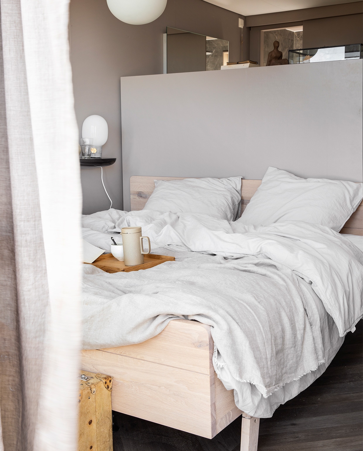 De wand is geschilderd in kleur Light Grey, per liter vanaf € 18,95, gordijnen Droplet Zand lichtdoorlatend met ring, 140x280 cm € 49,-, beddengoed Natural Stone Nude, 240x200/220 € 119,95, boxspring Cinnamon uit de lifestyle collectie van vtwonen vanaf € 1860,-.M.m.v.: vtwonen.nl (oranje kussen van HK Living), imbarro.nl (lichtroze kussen), ricebyrice.com (plaid), loods5.nl (rotan mand met leren lus). Overig privébezit. vtwonen 07-2019 | styling Kim van Rossenberg en styling Danielle Verheul | fotografie Peggy Janssen