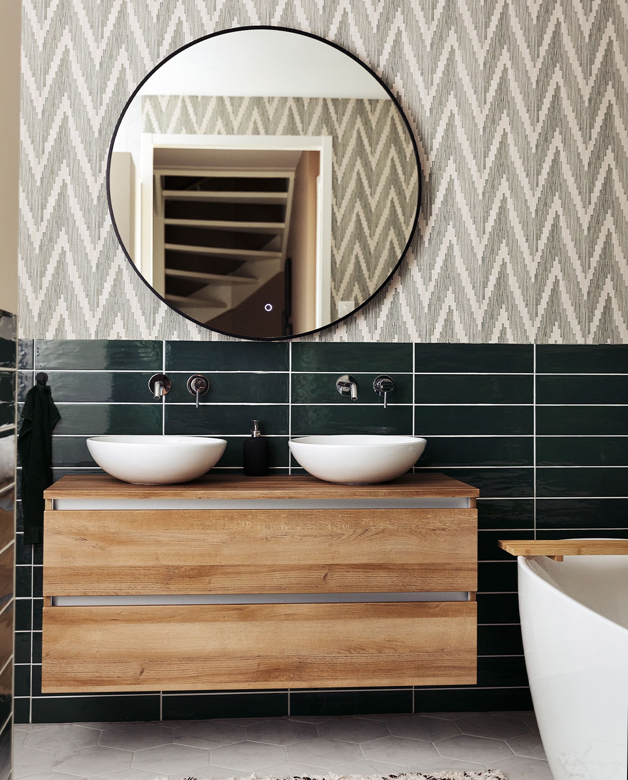Badkamerkast Unihopper. Wastafelkommen Solid Surface. Kranen en vrijstaand bad ADW. Spiegel Best Design. Tegels Sartoria. Behang BN Walls. Kleed H&amp;M Home. vtwonen 10-2021 | Styling Ilona Jongepier | Fotografie Dana van Leeuwen | Tekst Anne van den Dool