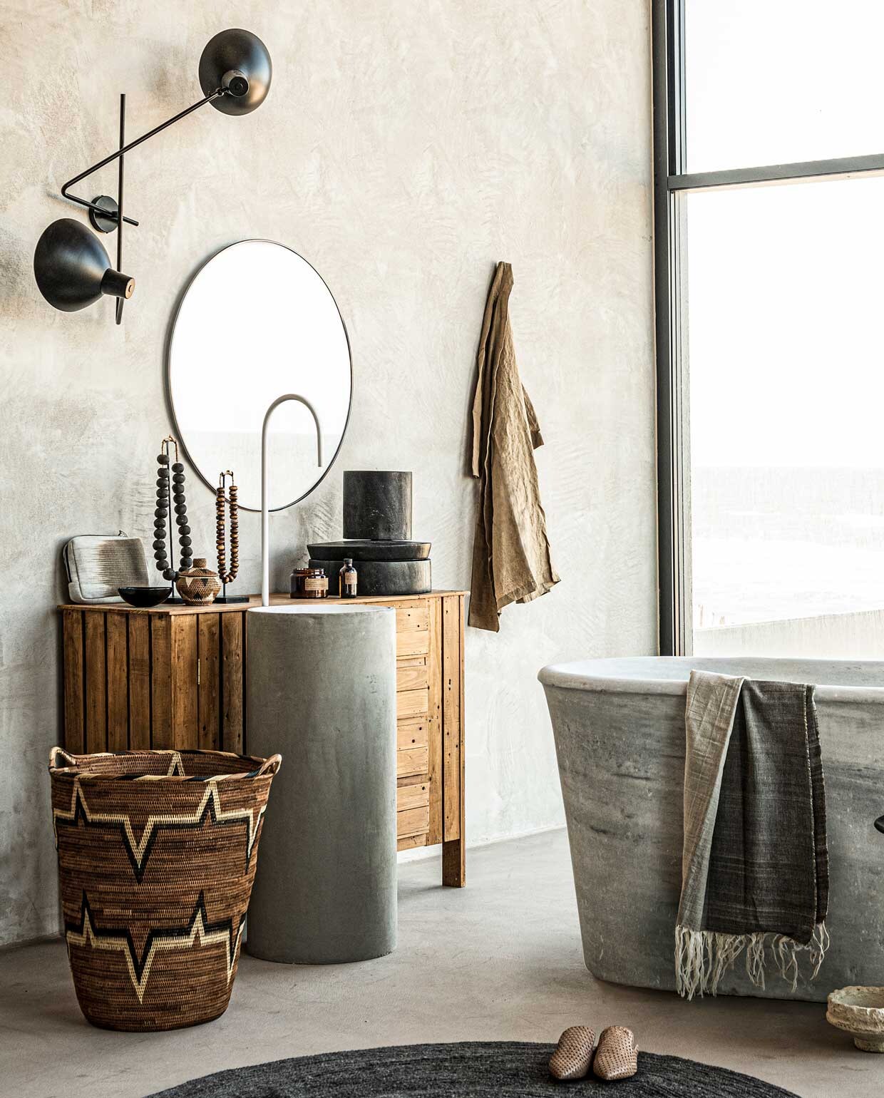 Spiegel Umbra Hubba Ø 86,4 cm € 150,-, wollen vloerkleed Bloomingville,Ø 140 cm € 155,- (vtwonen.nl). Op maat gemaakt wastafelmeubel van hout met waskom aan de voorkant Combitex, prijs op aanvraag (com-anders.nl). Mand Lalibu met handvaten, 53×59 cm € 459,-, witte graanpot van papier-maché op de grond, 11×23 cm € 49,- (couleurlocale.eu). Geurkaars op wastafelmeubel € 39,90, flesje voor geurstokjes € 27,90, bruin kommetje € 12,90,- (letoile.store). Marmeren bad € 6000,- (oudebouw­materialen.nl). Hamamdoek 100×250 cm € 130,-, stoffen etui € 45,- (badenbaden.nl). Linnen badjas € 39,99, slippers € 49,99 (hm.com). Grote kralenketting € 109,-, kleine kralenketting € 79,- (o-live.nl). Overig privébezit of bezit van de locatie (republiekbloemendaal.nl). JA | vtwonen 09-2020 | styling Liza Wassenaar | fotografie Sjoerd Eickmans