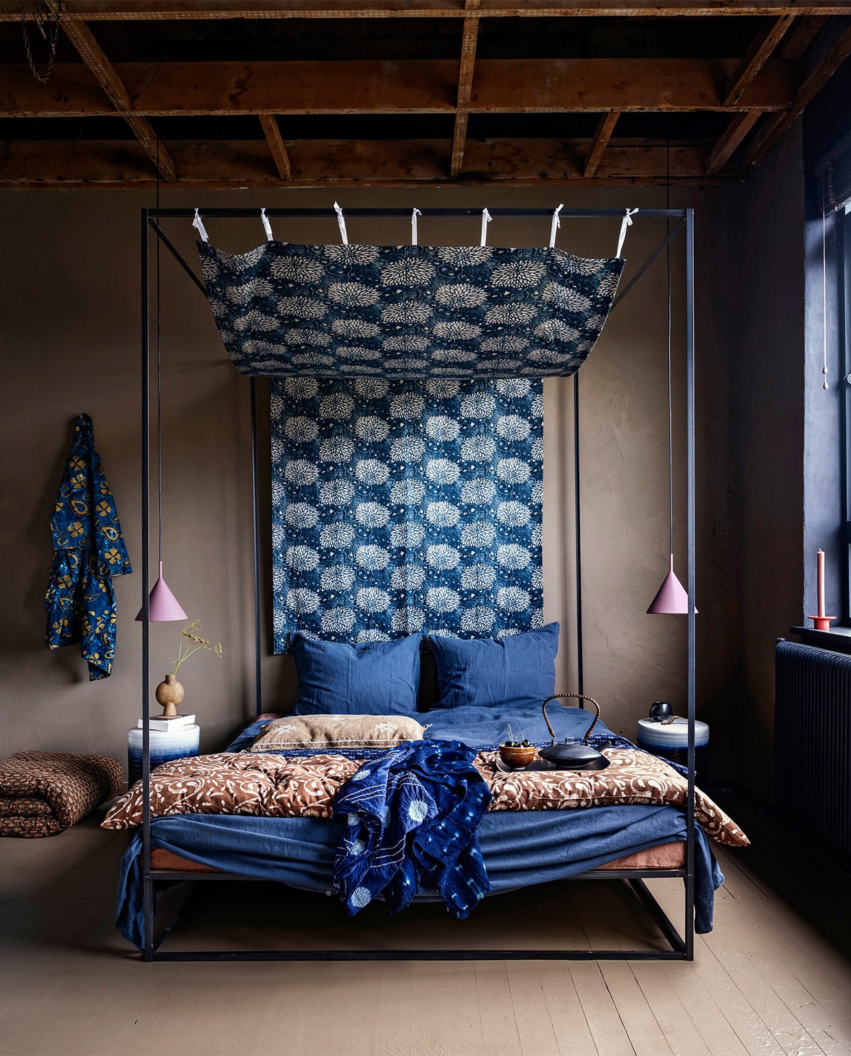 Op de muur krijtverf Mexican Sand, op de vloer lakverf Mexican Sand(pure-original.nl). Hemelbed, op maat gemaakt (com-anders.nl). Linnen-katoenmix beddengoed lits-jumeaux met 2 kussenslopen in Midnight Blue (suite702.com). Matrasjes met batikdessin in Midbruin groot matras opgerold allebei Madam Stoltz (deens.nl). Zandbruin kussen met borduursels (zenza.nl). Grof geweven indigo doek uit Mali (basketbeadsbasics.nl). Zijden sjaal in tiedye kamerjas van batik blauw-goudgeel(capsicum.nl). Hanglampen, kommen per 4 stukswilgenhouten dienblad allemaal HKliving (vtwonen.nl). Blauw-witte keramieken bijzettafels (polspotten.nl). Vaas zwarte mok met oor en theepot (101cph.com). Rode kandelaar (eijerkamp.nl). JA vtwonen 10-2020 | styling Marianne Luning | fotografie Stan Koolen